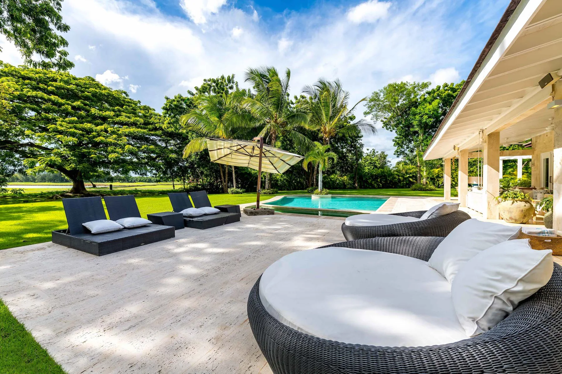 A sunny poolside patio with outdoor seating and a swimming pool.