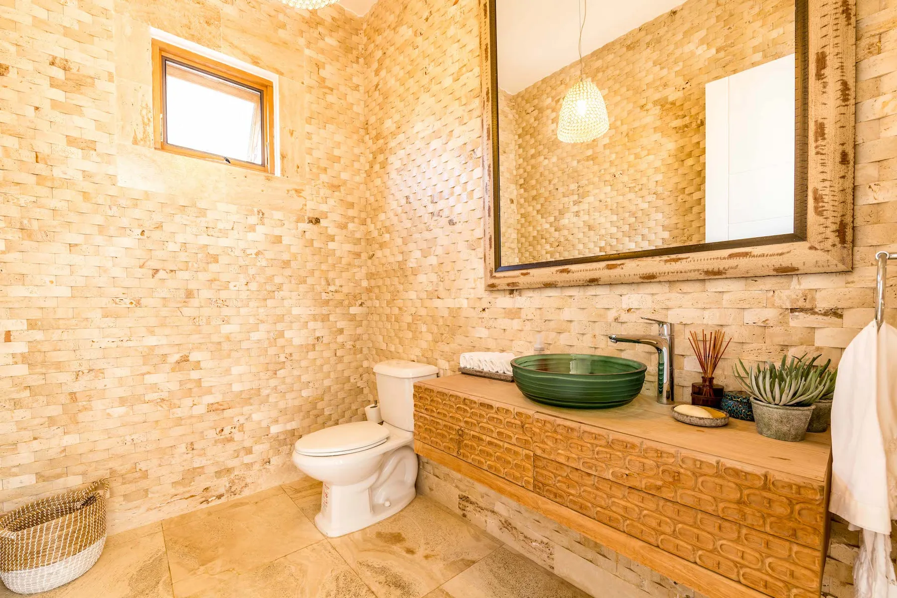 Un baño con azulejos, inodoro, tocador y un espejo grande.