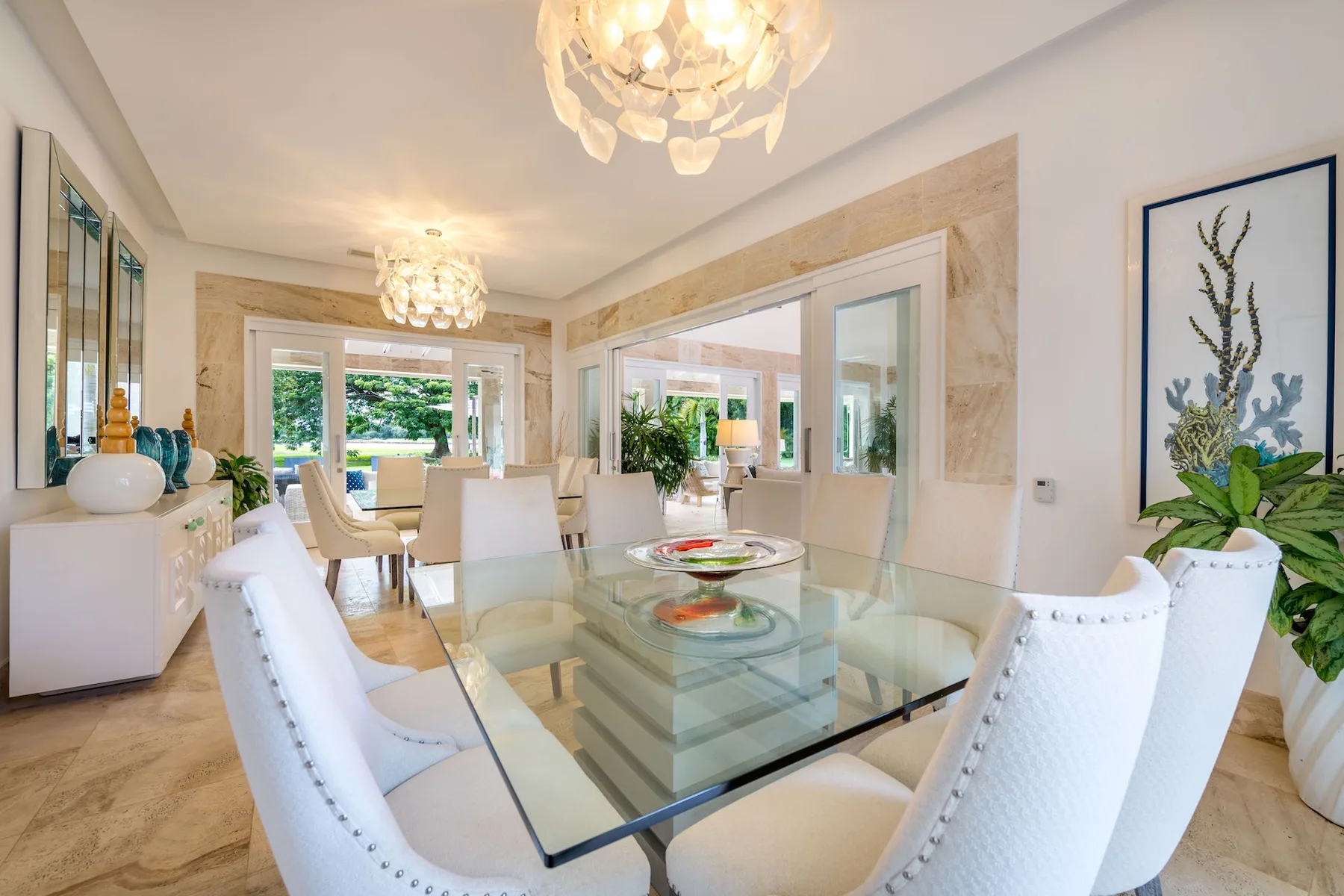 Un comedor luminoso con una mesa de vidrio y asientos tapizados blancos.