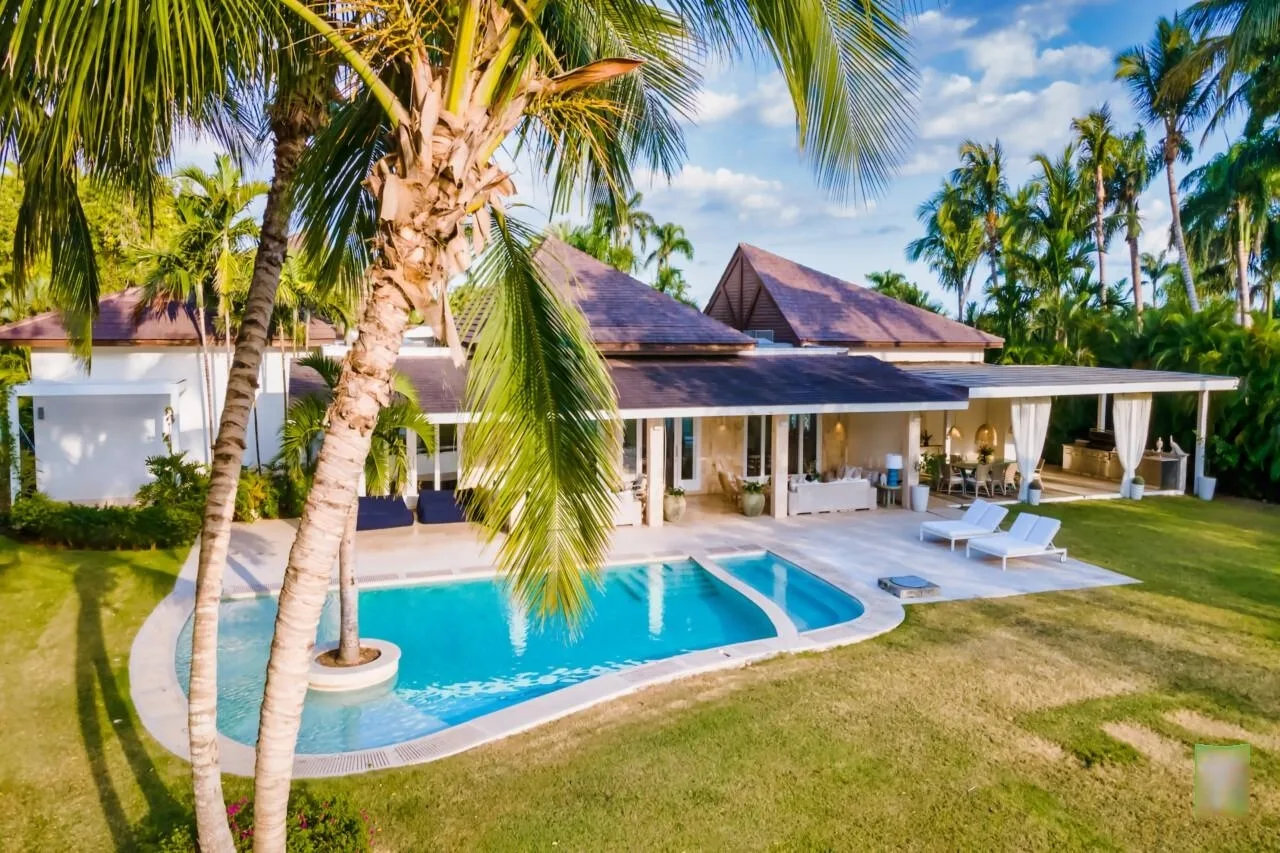A tropical house with a swimming pool and covered outdoor seating.