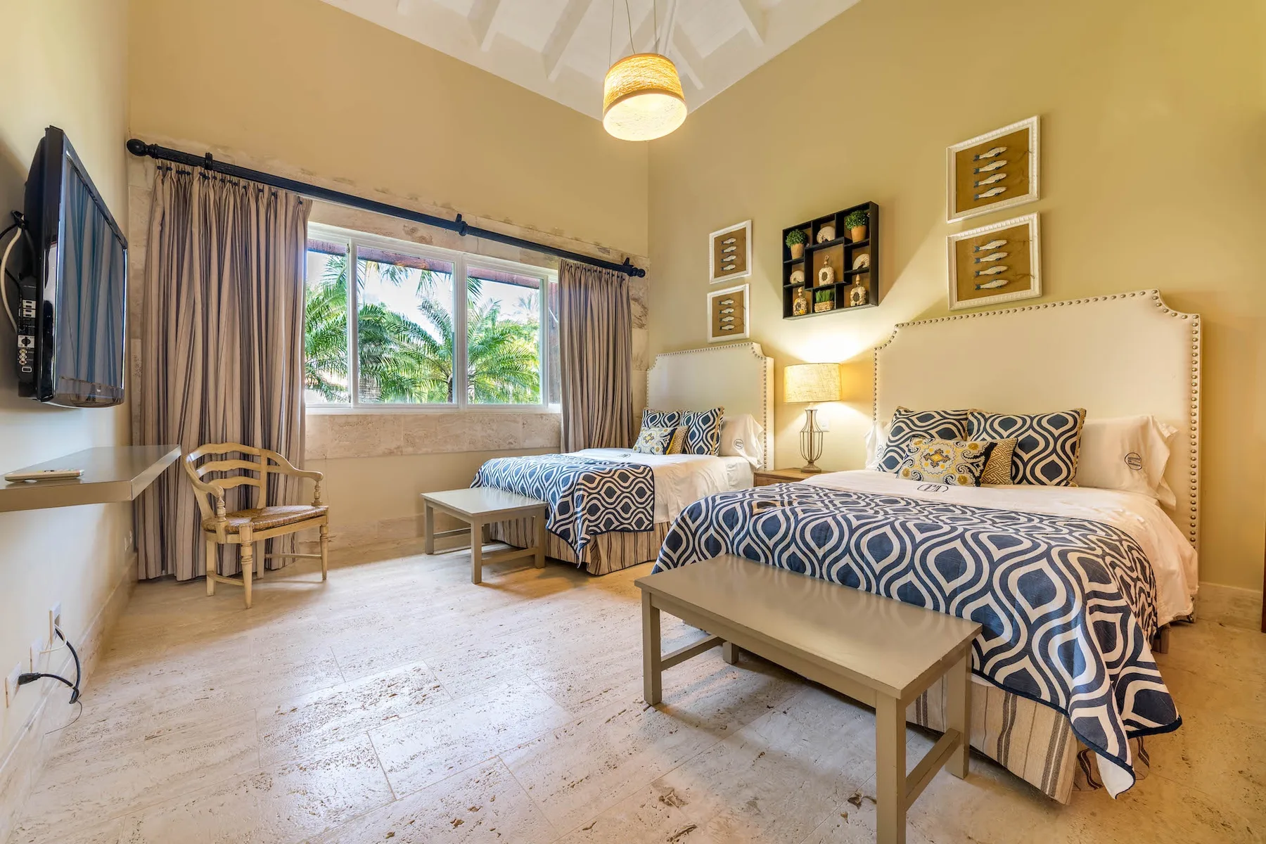 A bedroom with two beds, a window, and a small table.