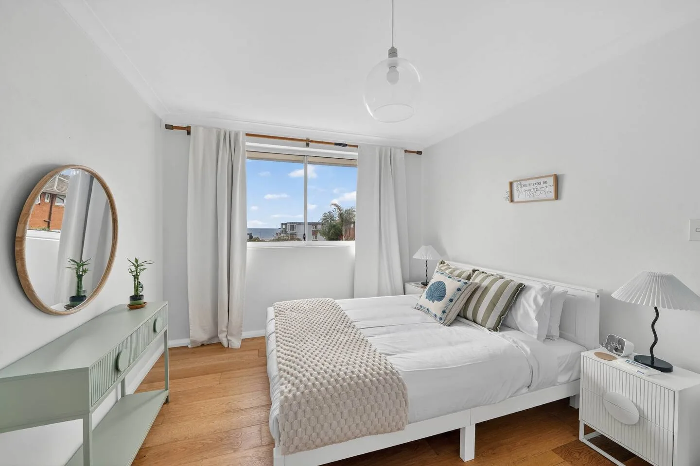 Wake refreshed in the bedroom, where a queen bed, built-in wardrobe and soft natural light create a peaceful retreat with distant sea views.