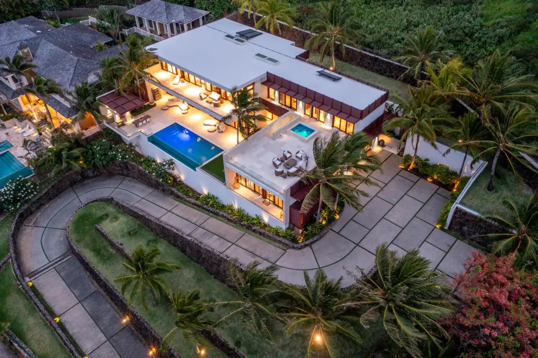 An aerial view of a modern building with a swimming pool and landscaped grounds.
