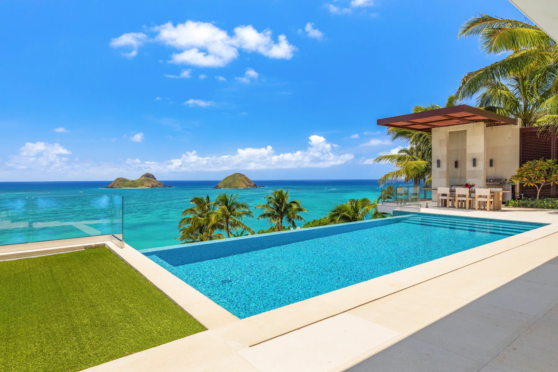 A swimming pool overlooks the ocean beside a modern building.