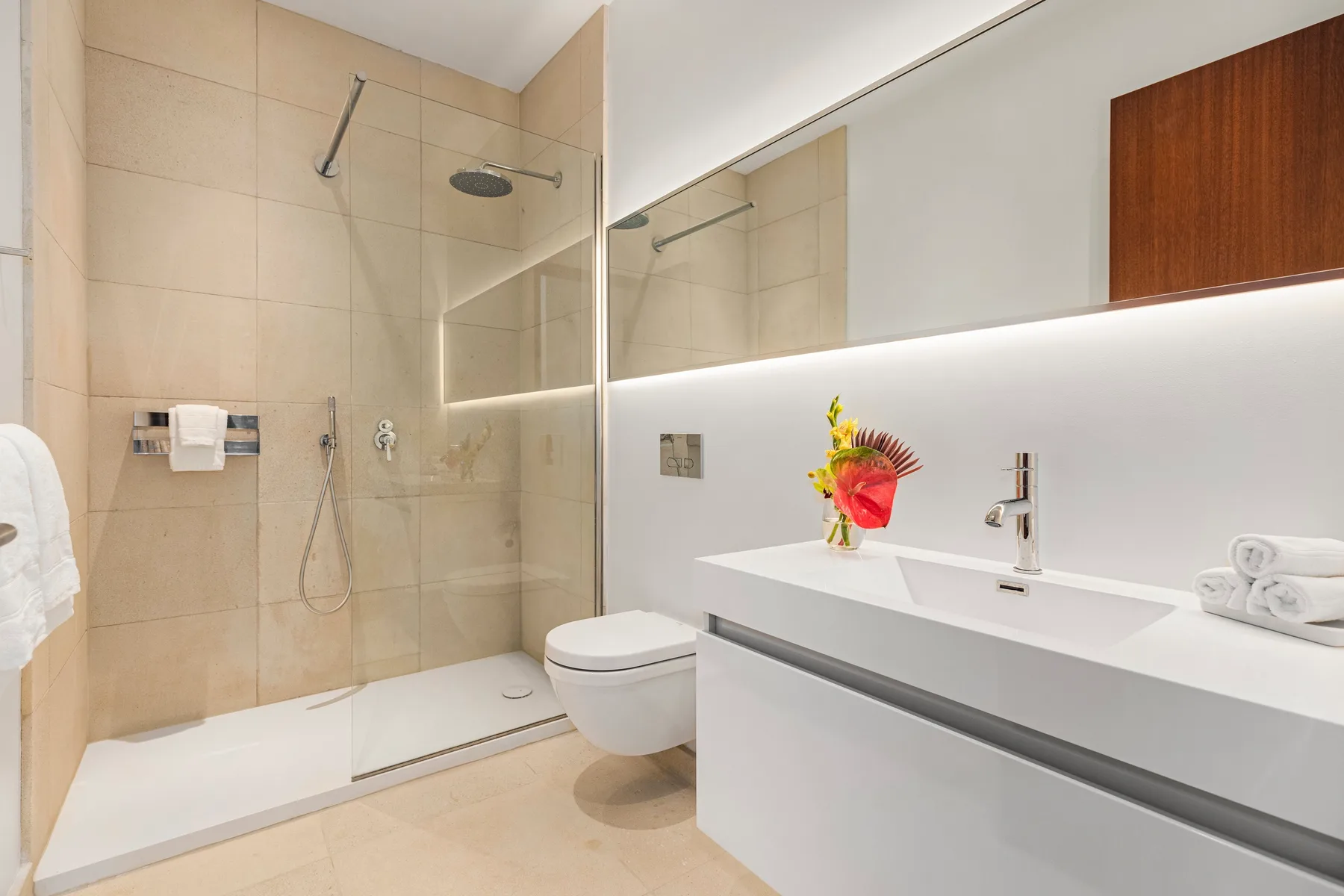 A modern bathroom with a glass shower, toilet, and white vanity.