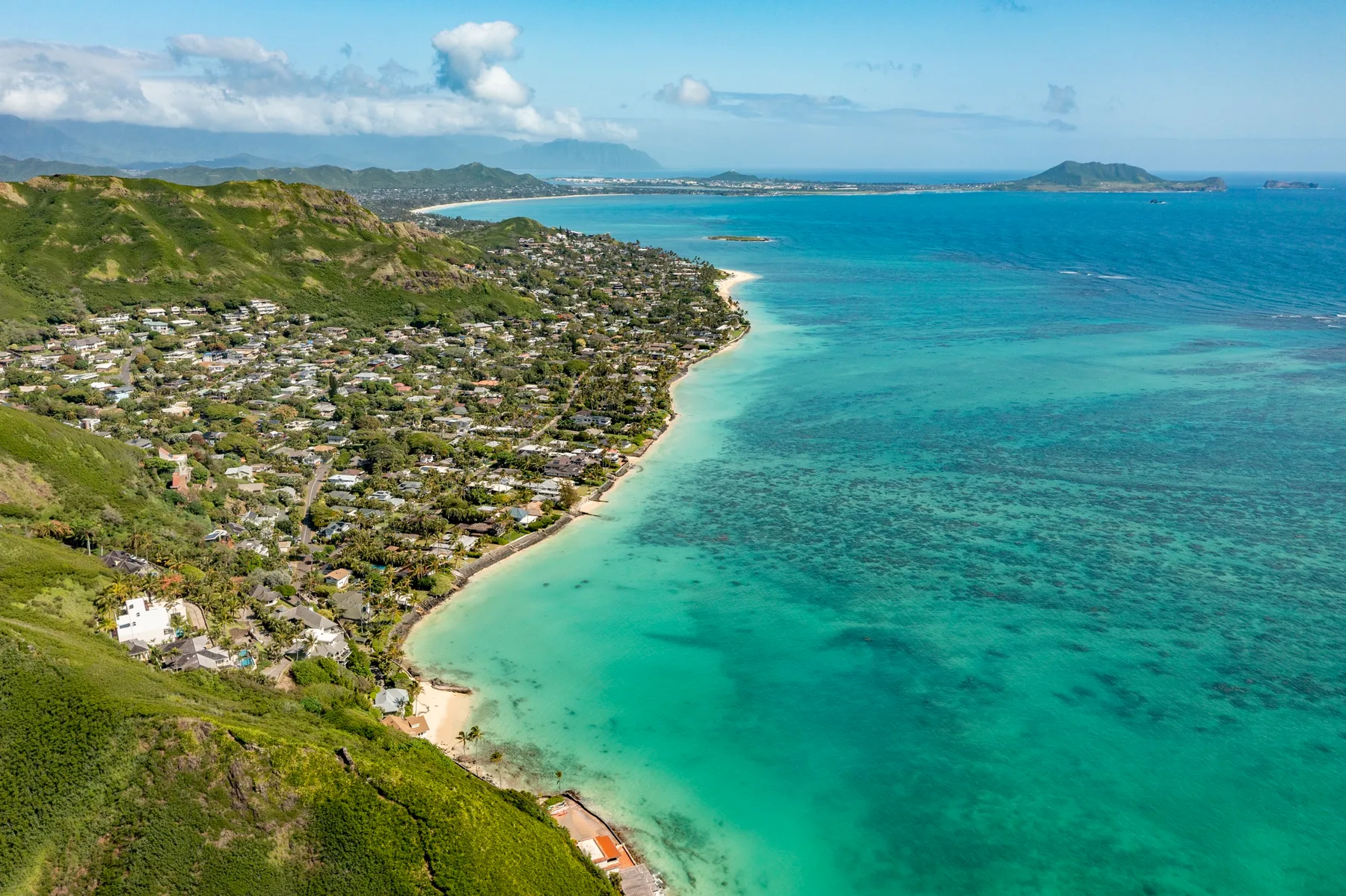 Aerial coastal view of a shoreline community beside turquoise water.