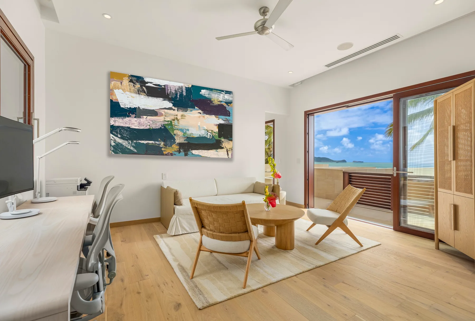 A bright living area with seating, a dining table, and wide glass doors opening to a balcony.