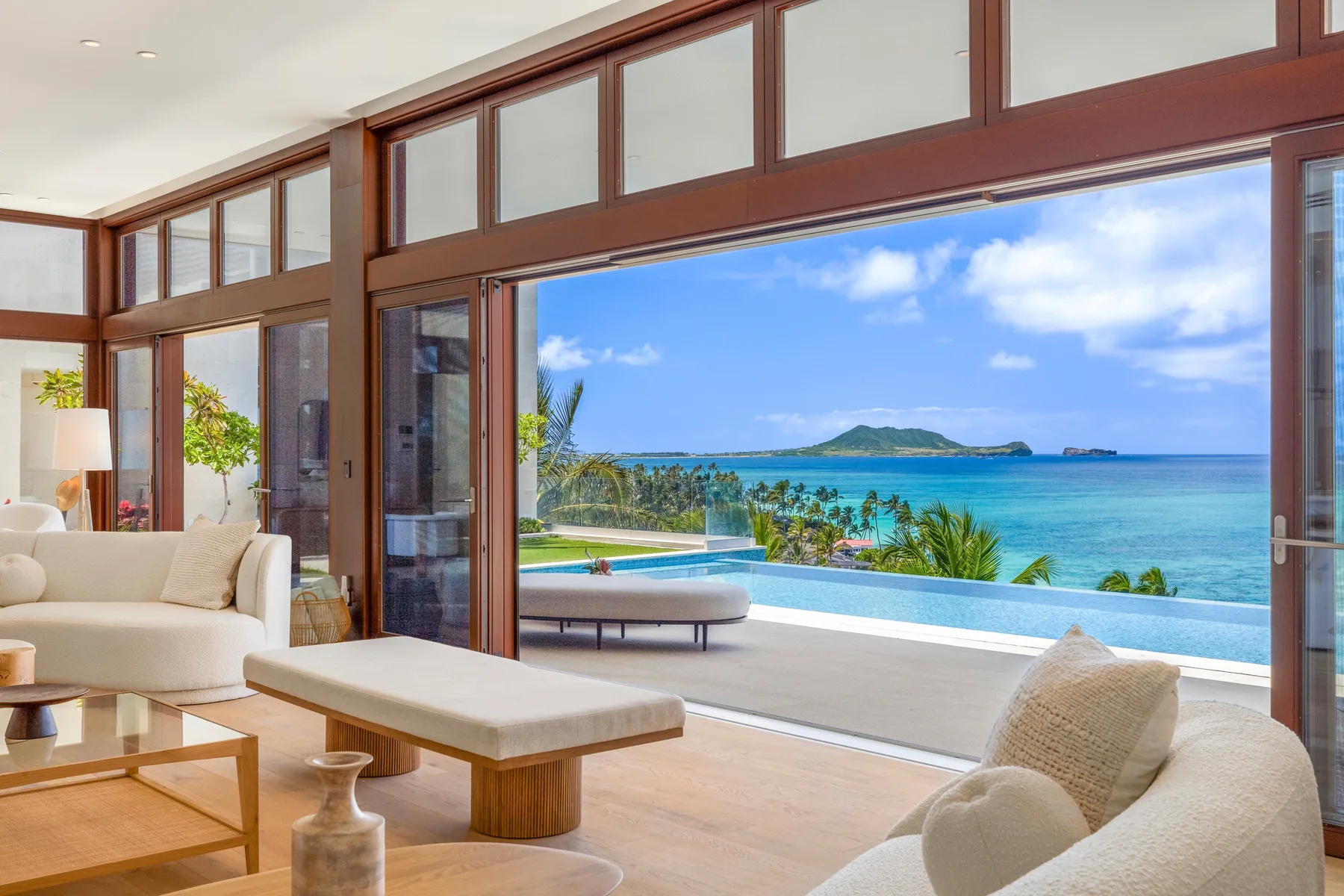 A bright living room opens onto a terrace overlooking a pool and the sea.