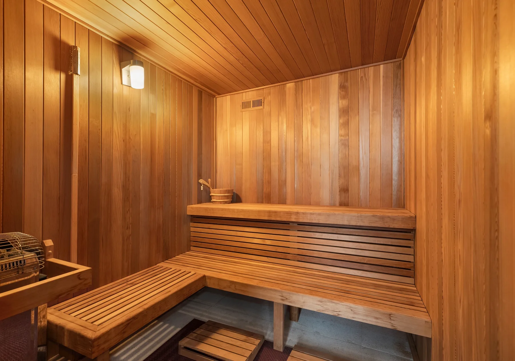 A wood-paneled sauna with tiered wooden seating and a heater.