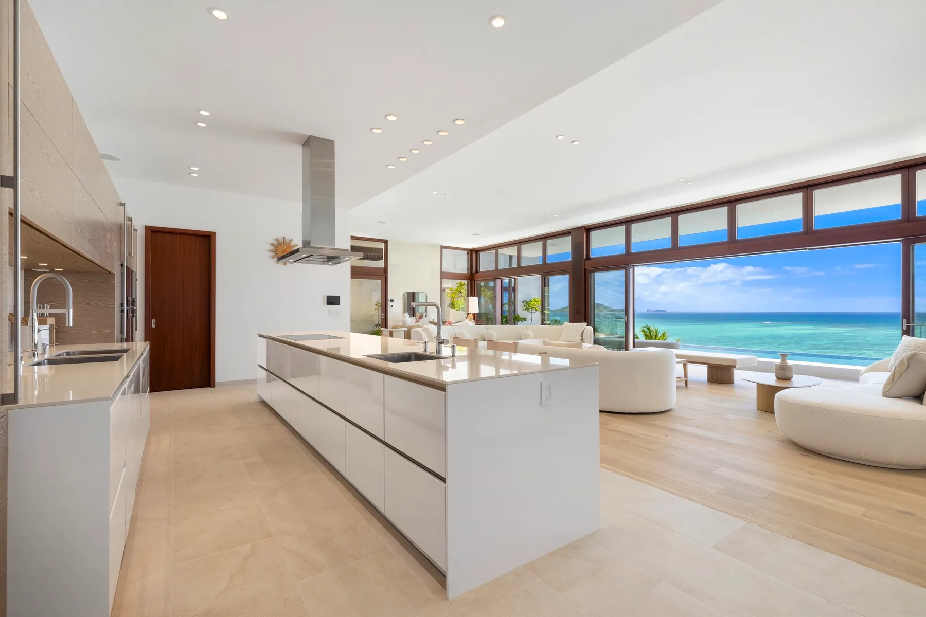 A bright open kitchen and seating area overlook the ocean through wide windows.