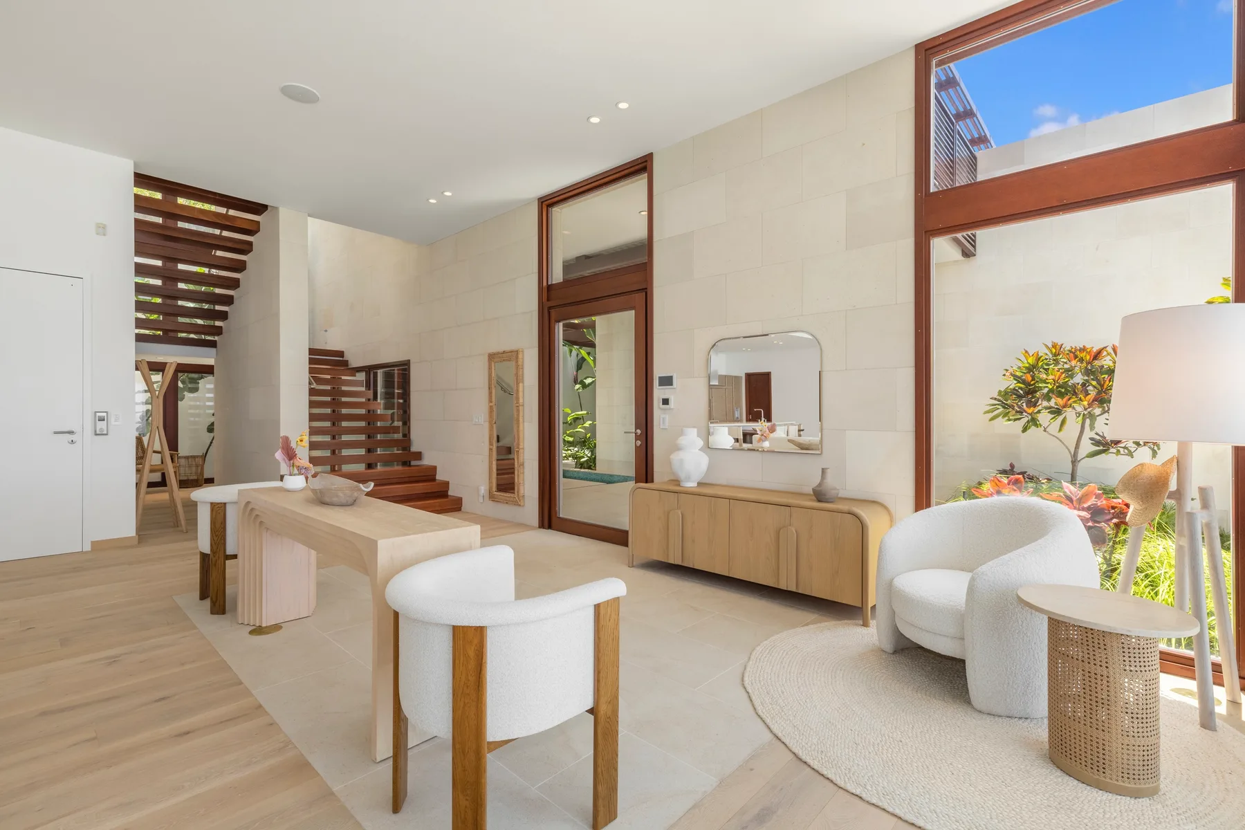 A bright living area with a dining table, lounge seating, and large windows.