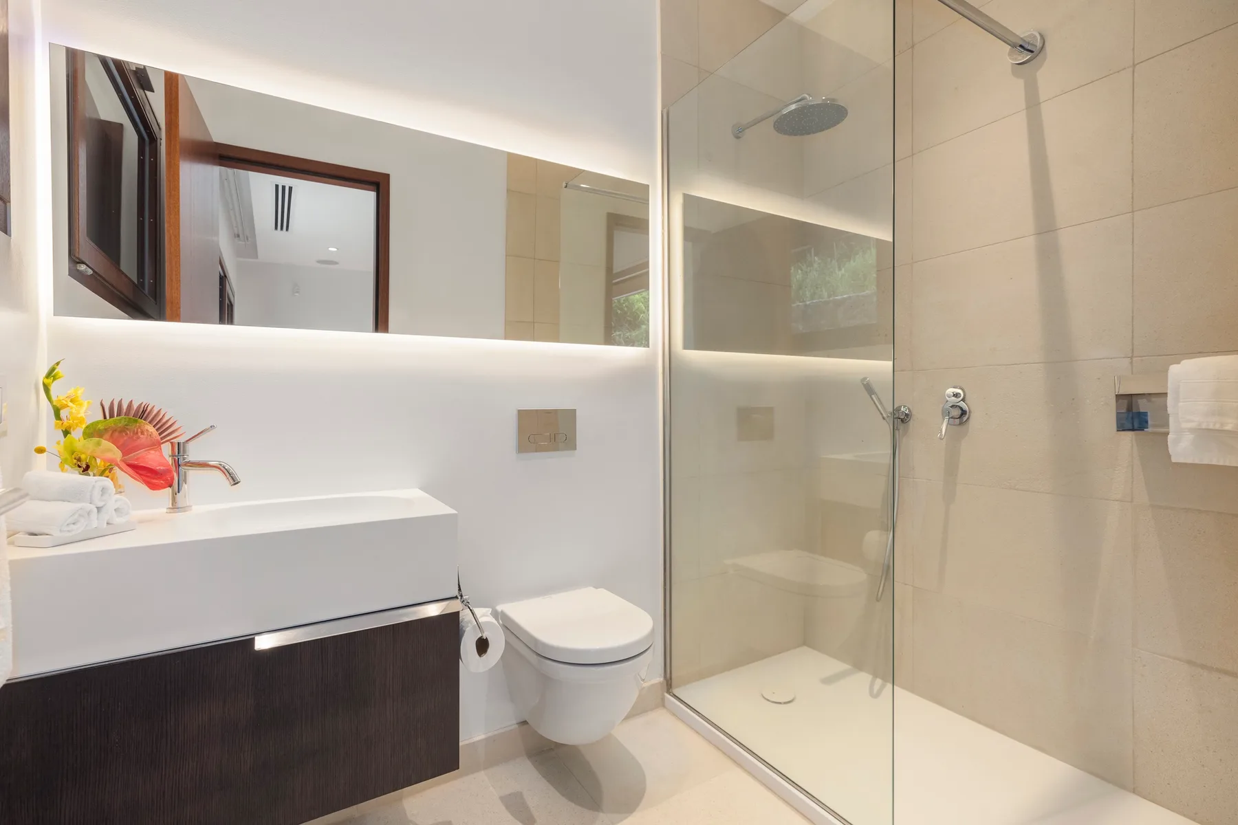 A modern bathroom with a glass shower and a wall-mounted sink.