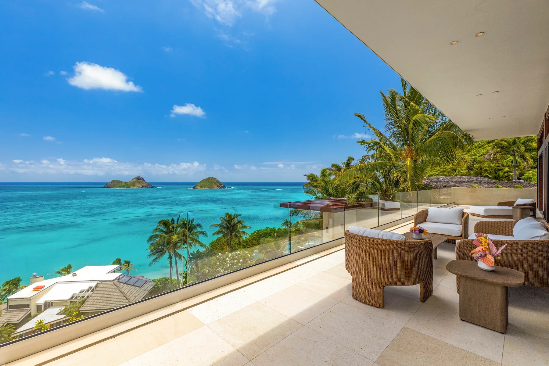 A furnished balcony overlooks turquoise water and small islands.