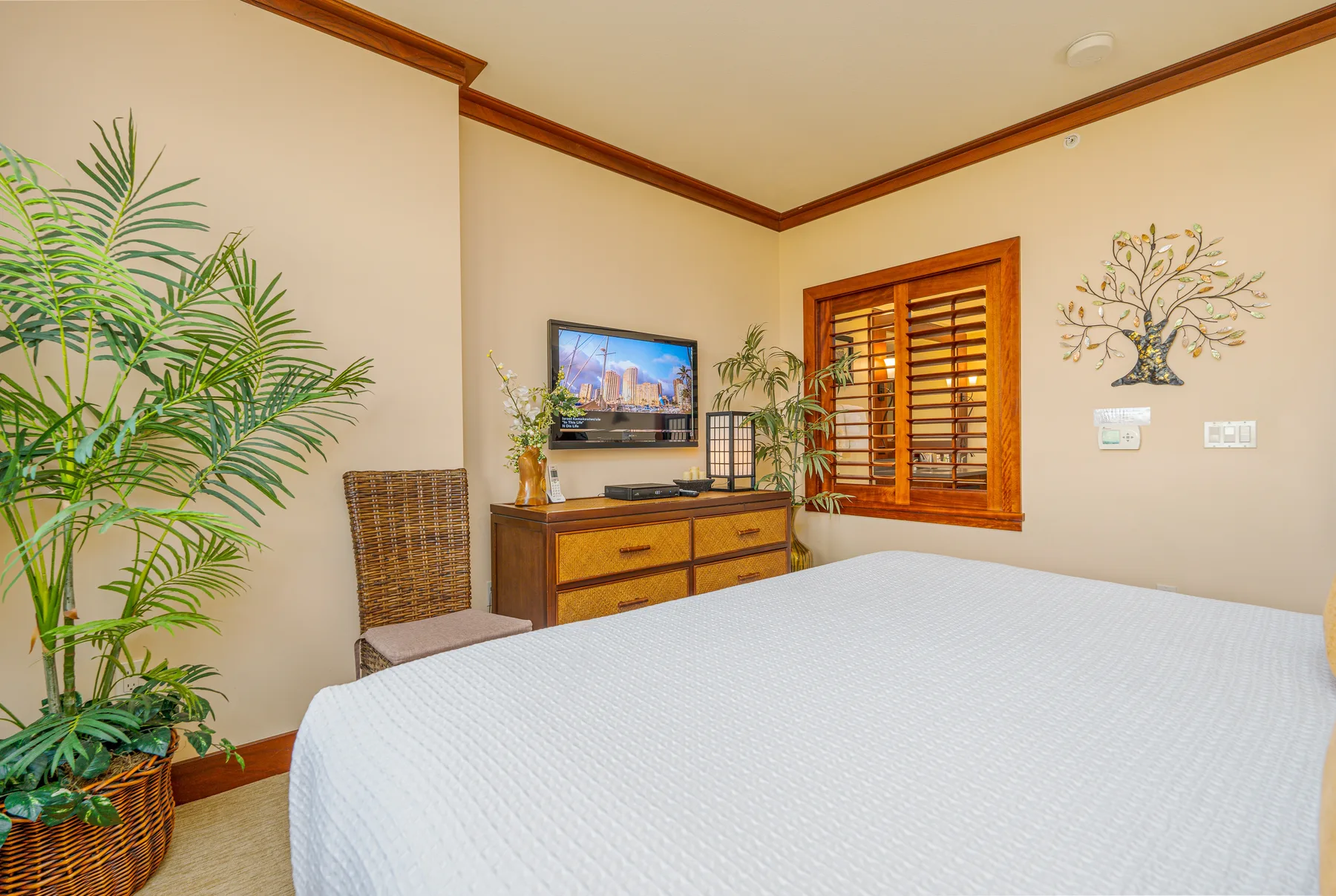 A bedroom with a bed, wooden dresser, and window with wooden blinds.