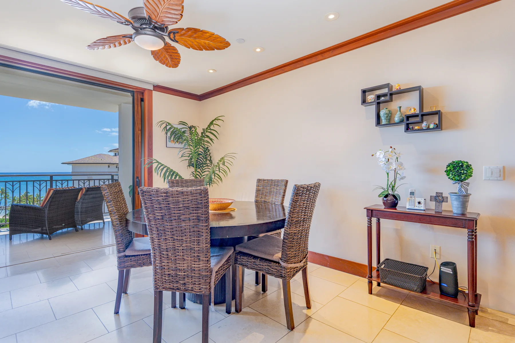 A dining area with a table and woven seating beside an open balcony.