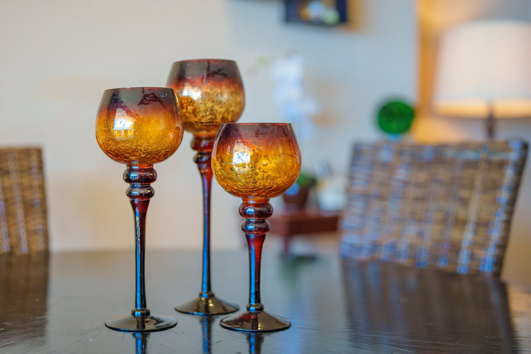 A dining area with three decorative amber glass candle holders on a table.