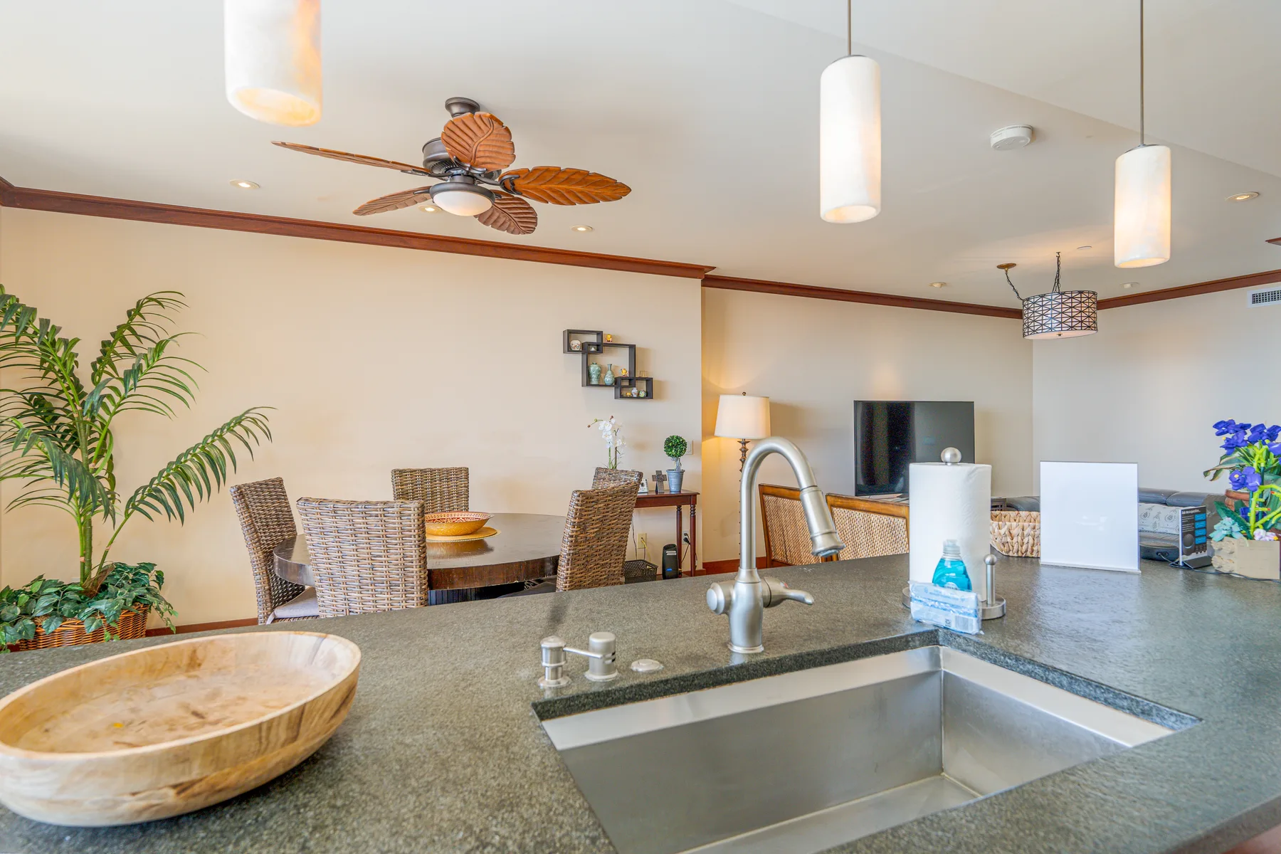 A kitchen island with a sink overlooks a dining area with a table and seating.