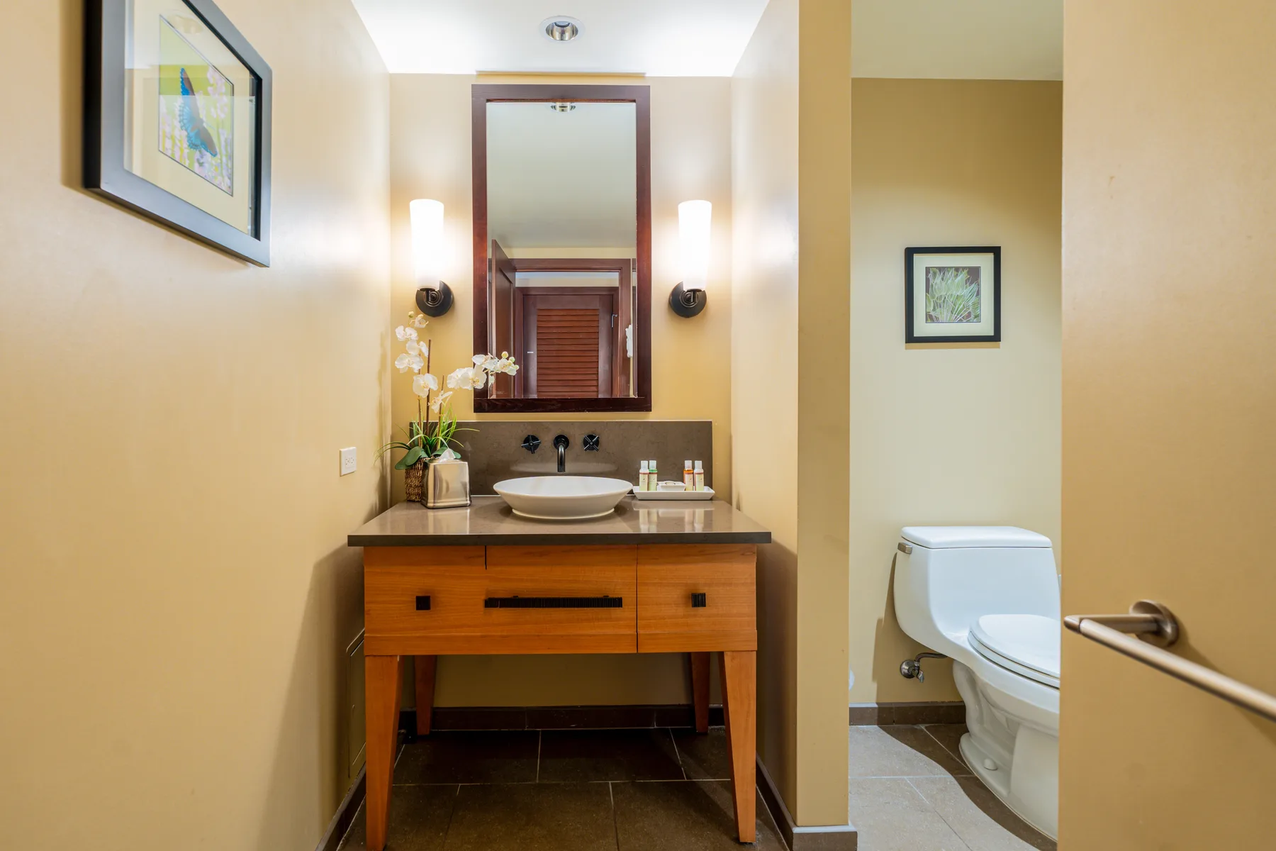 A bathroom with a wooden vanity, sink, and large mirror.