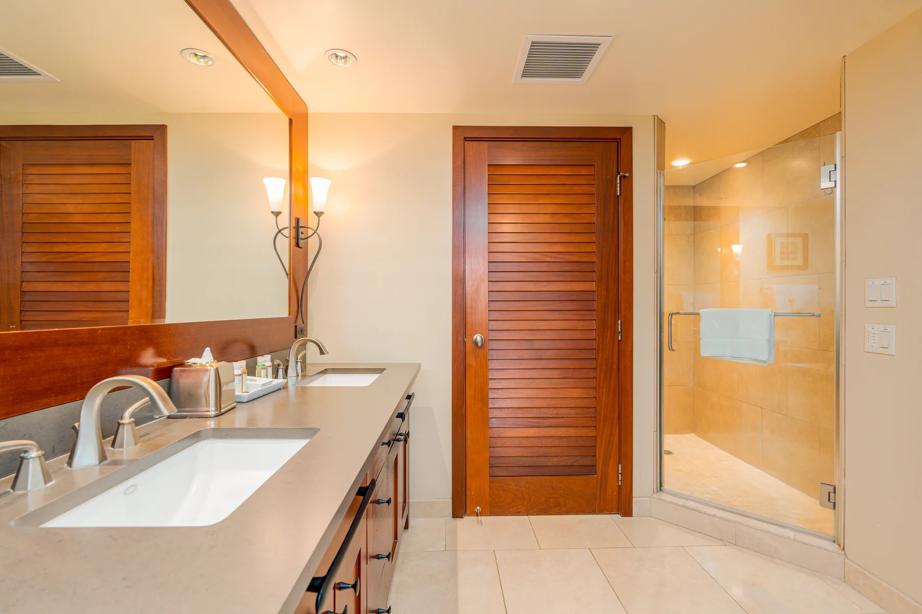 A bathroom vanity faces a wooden door beside a glass shower.