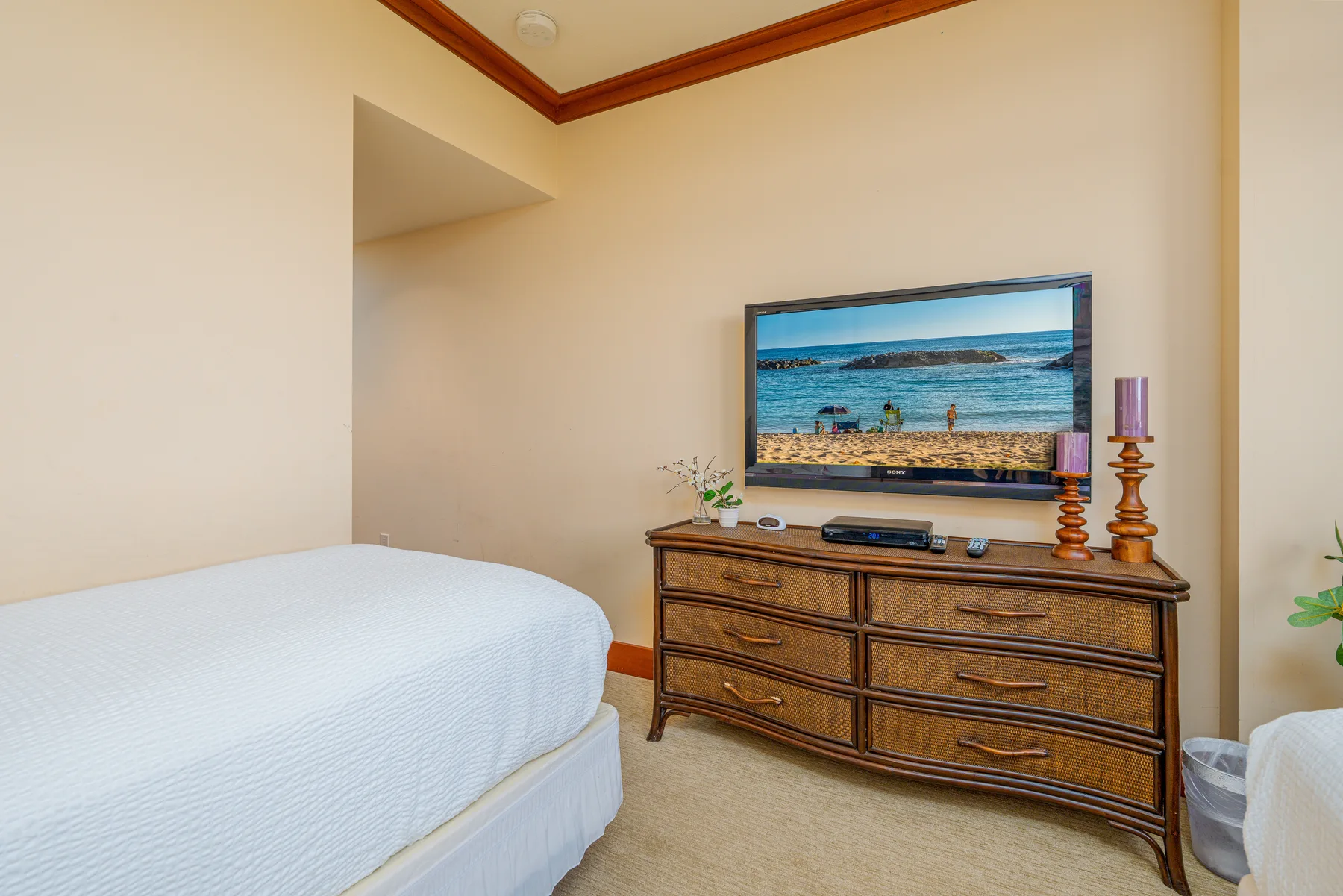A bedroom with a bed and a dresser topped by a television.