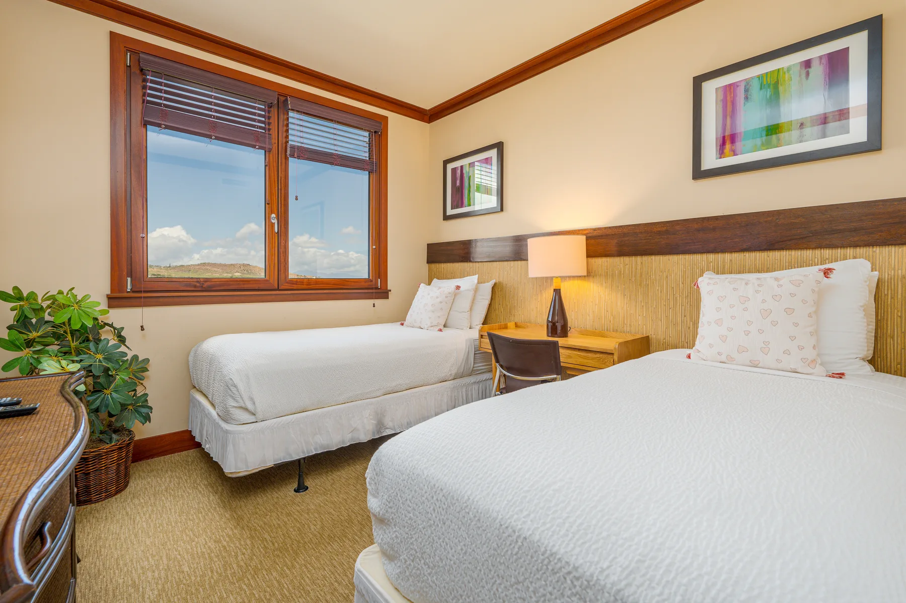 A bedroom with two beds, a bedside table, and a window.