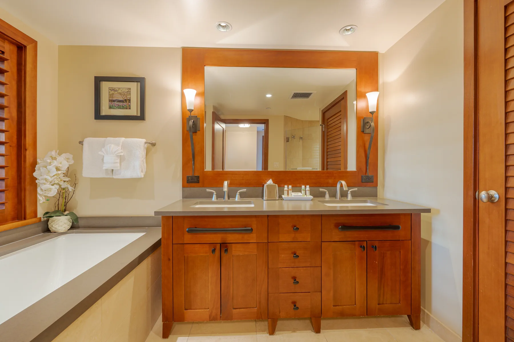 A bathroom with a wooden vanity and a large mirror above the sink.