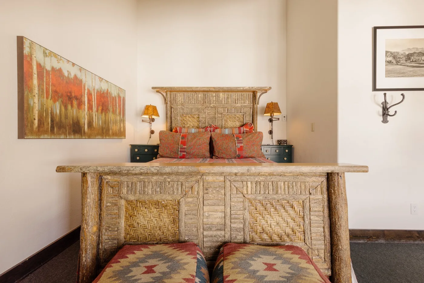 Un dormitorio con una cama de madera tallada y ropa de cama estampada y colorida.