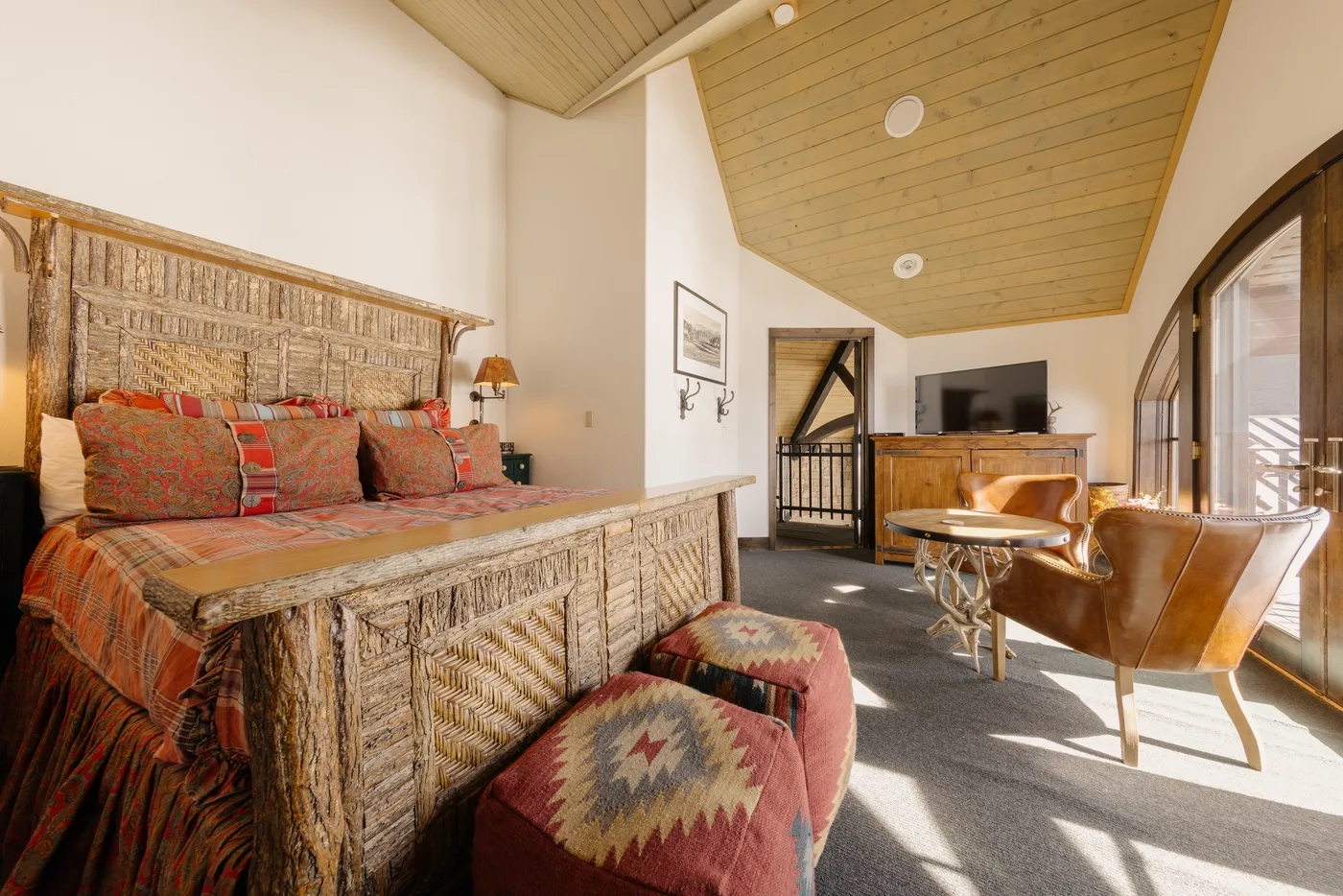 Dormitorio y zona de estar rústicos con cama, sillones y televisor.