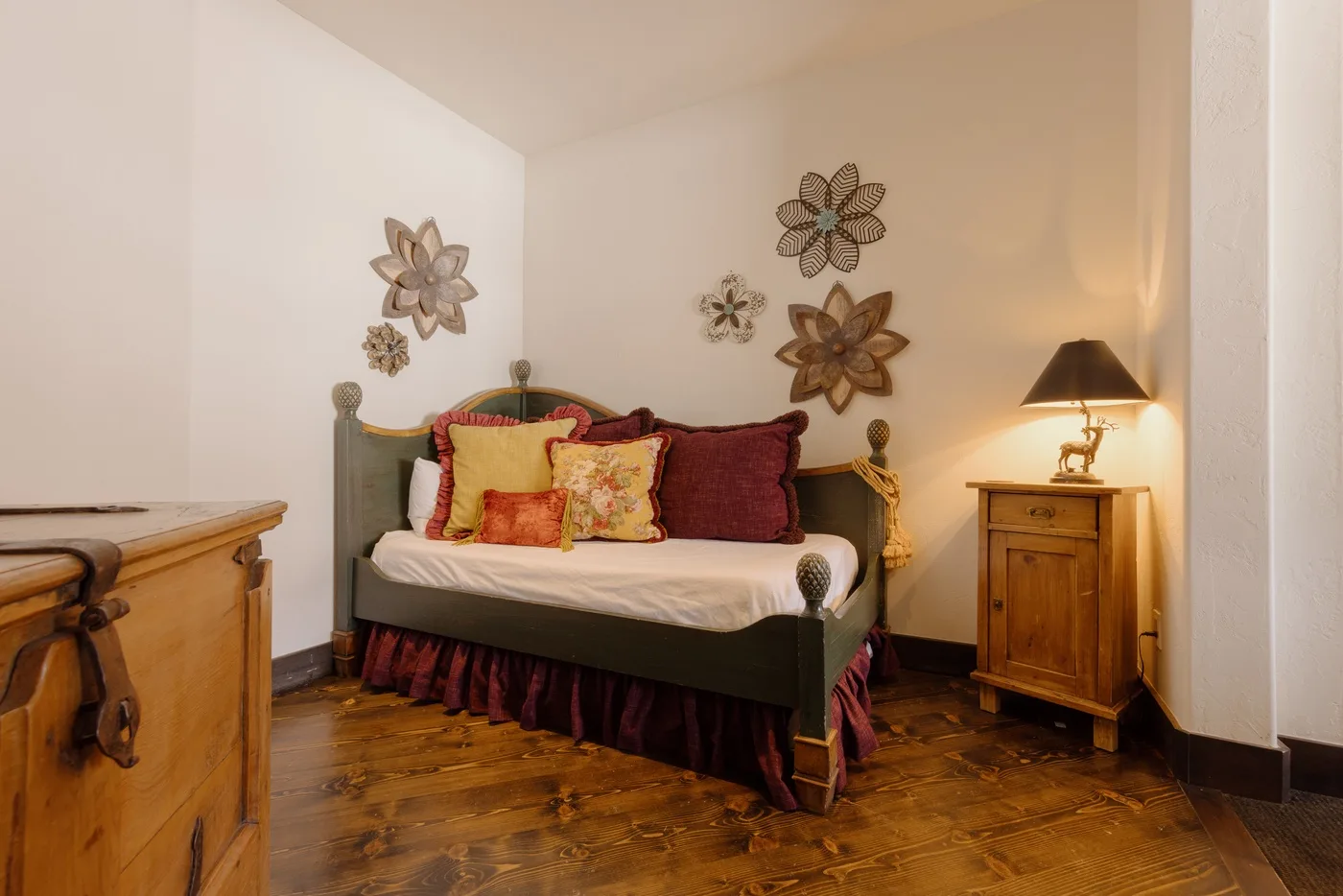 Un dormitorio con una cama, cojines de colores y adornos florales en la pared.