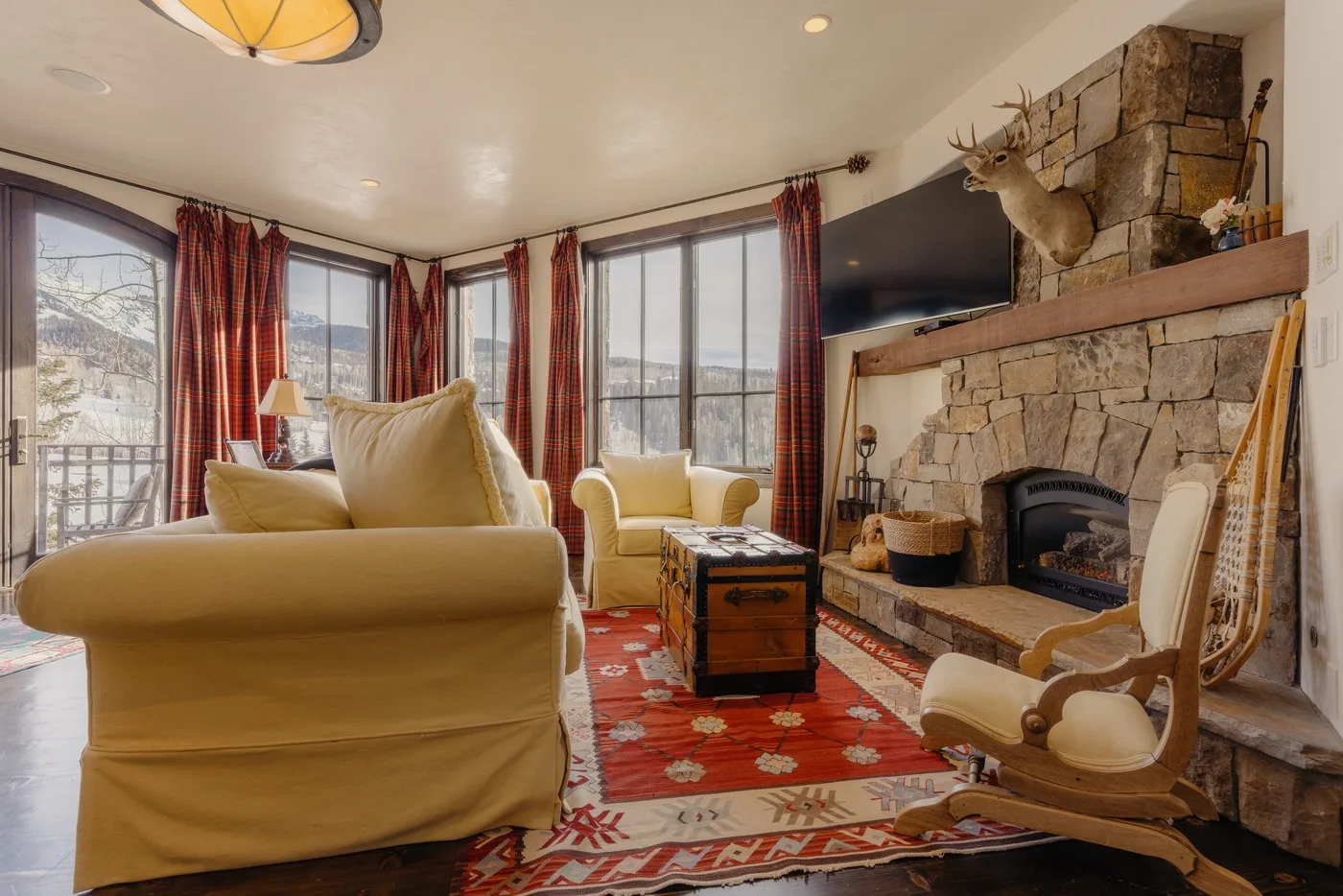Una sala de estar con asientos, una chimenea de piedra y ventanas grandes.