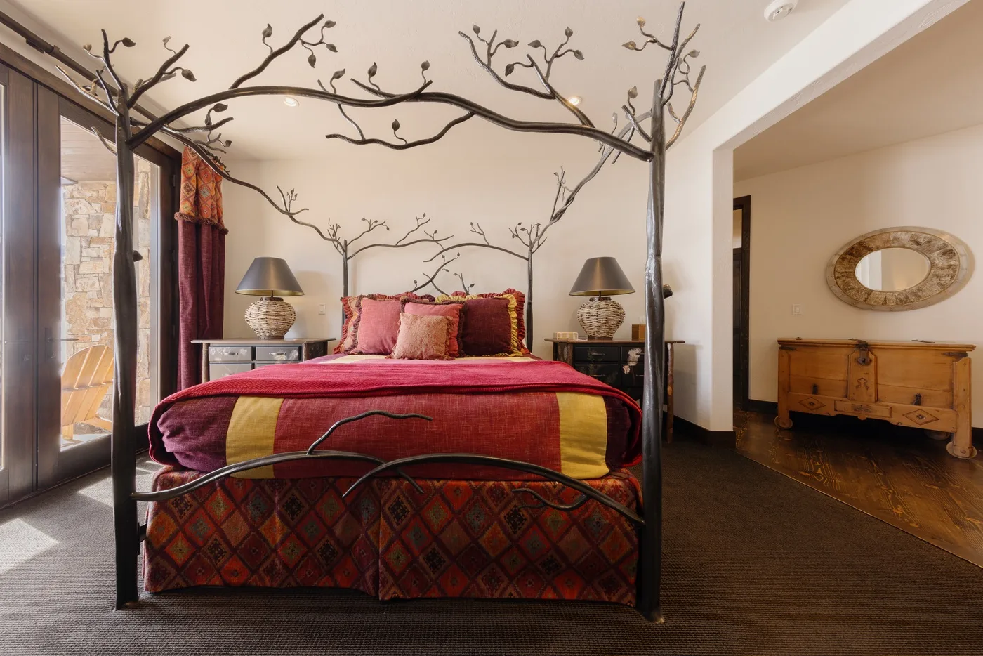 Un dormitorio con una cama roja bajo una estructura decorativa con ramas.