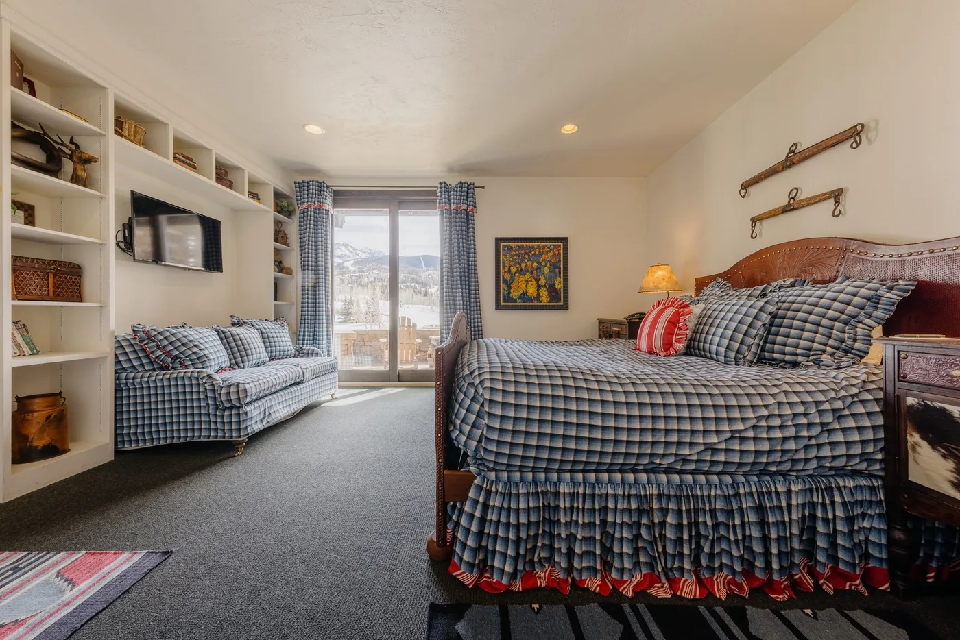 Dormitorio con una cama grande, una zona de estar y puertas de vidrio que dan a un balcón.