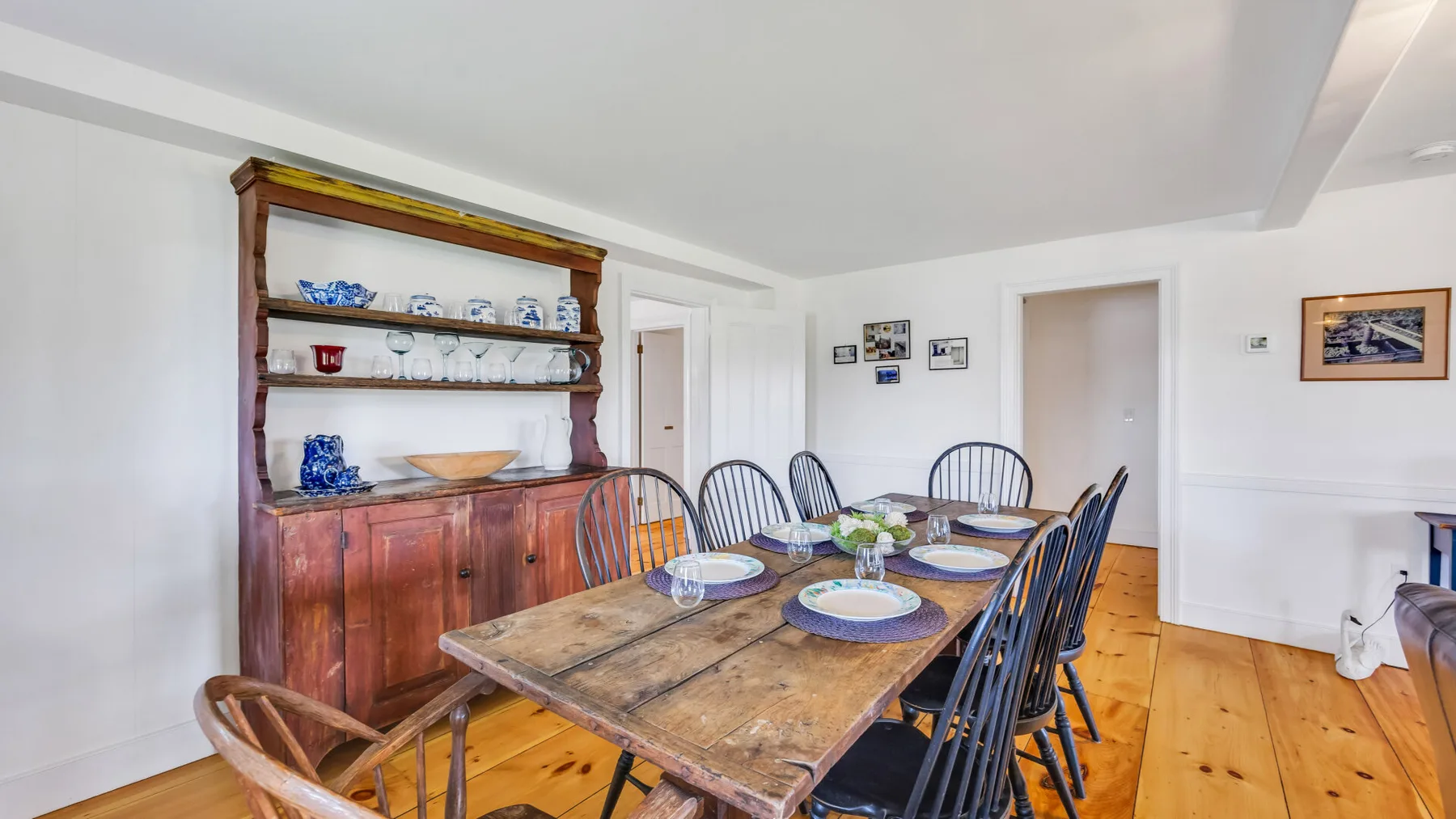 A dining room with a long wooden table and a display cabinet.