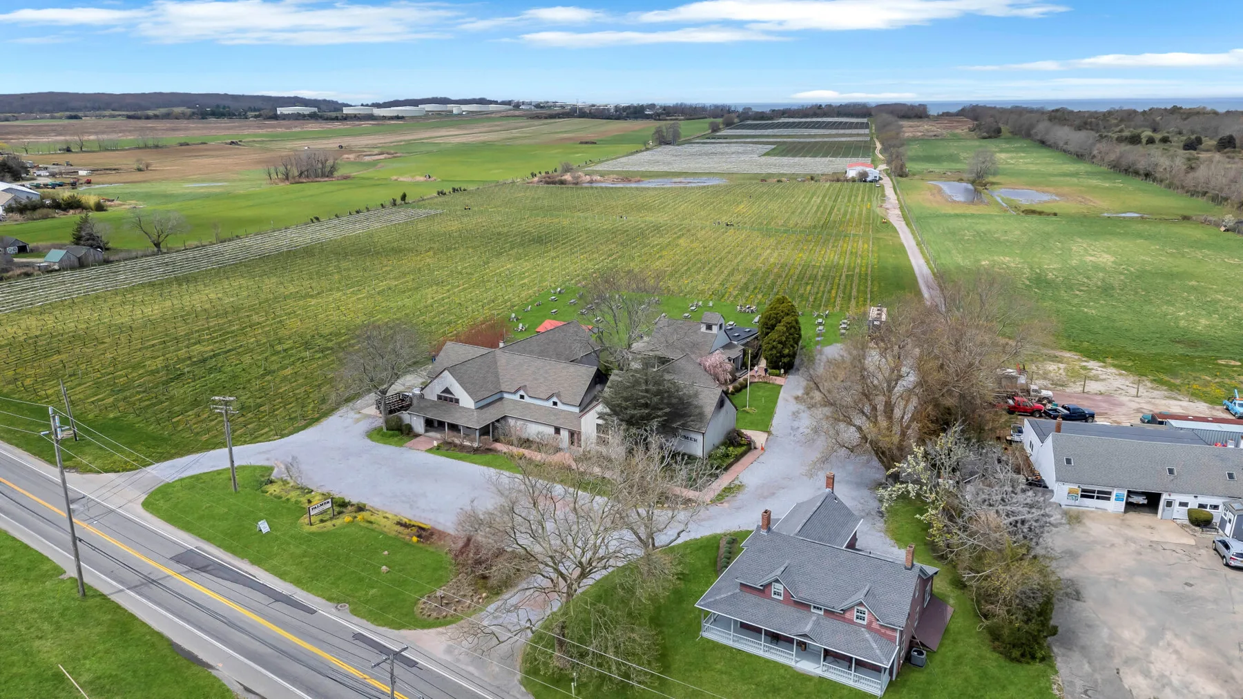 An aerial view shows a house beside a road, surrounded by fields.