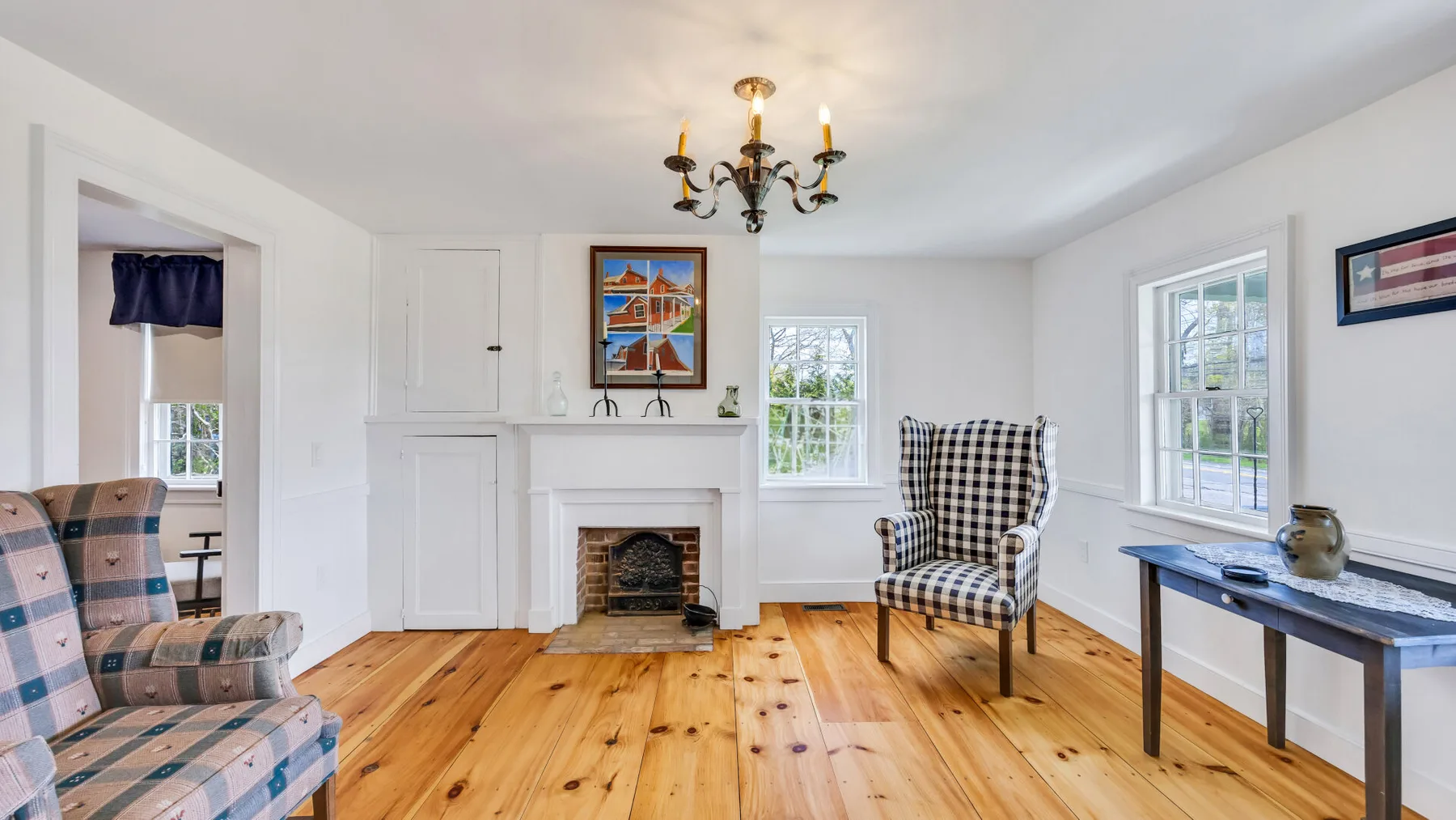 A bright living room with wooden floors, a fireplace, and a patterned armchair.