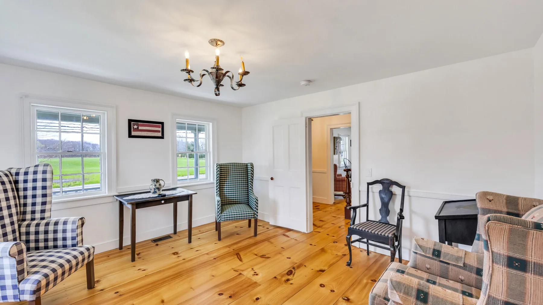 A bright living room with wood flooring and several seating areas.
