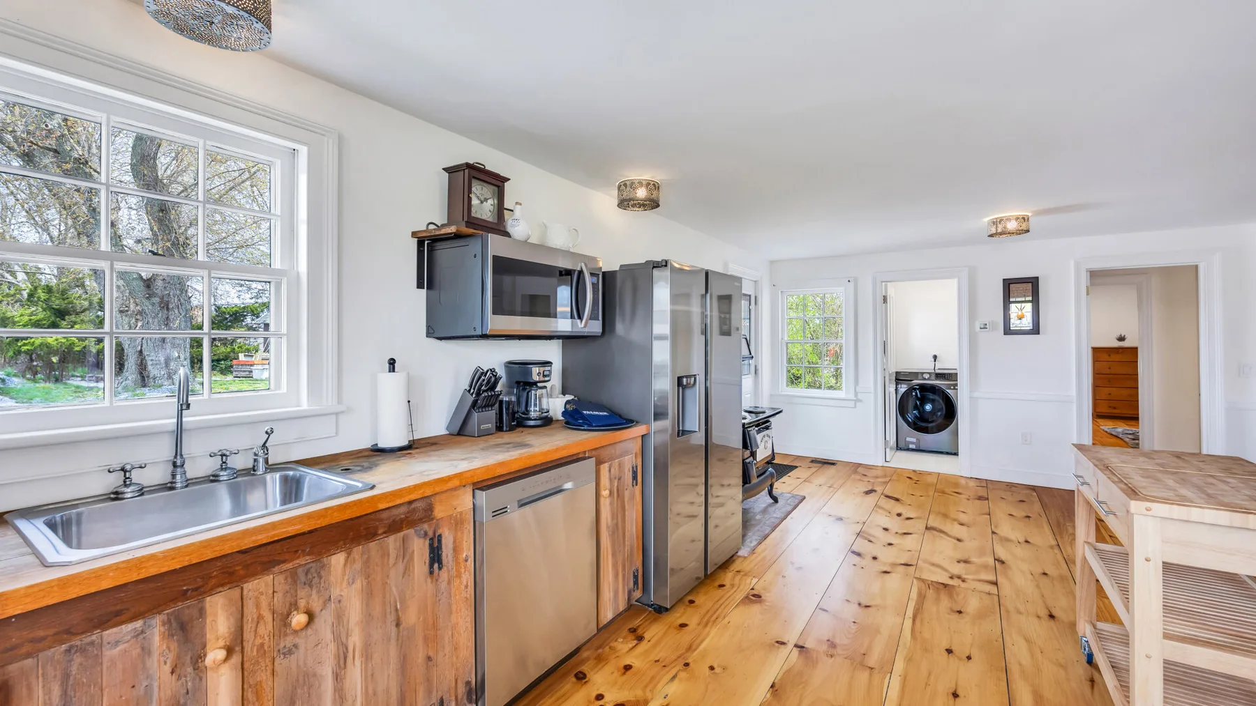 A bright kitchen with wooden countertops, stainless steel appliances, and a large window.