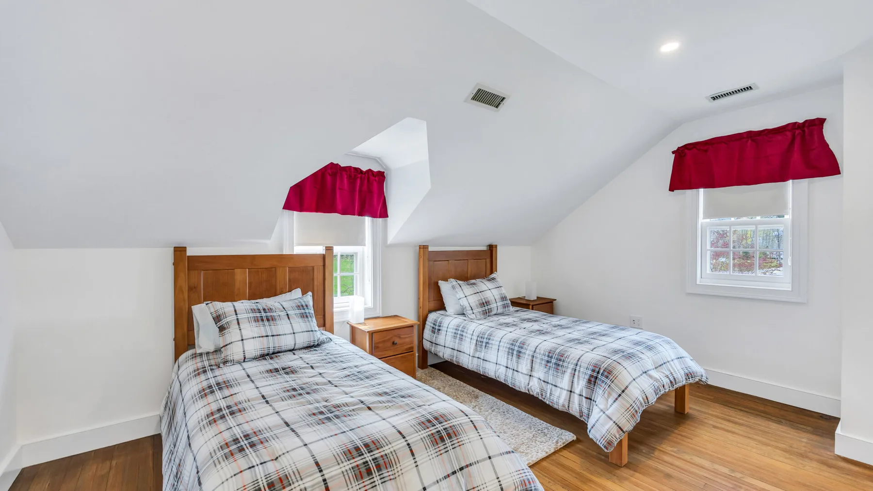 A bright bedroom with two beds dressed in matching plaid bedding.