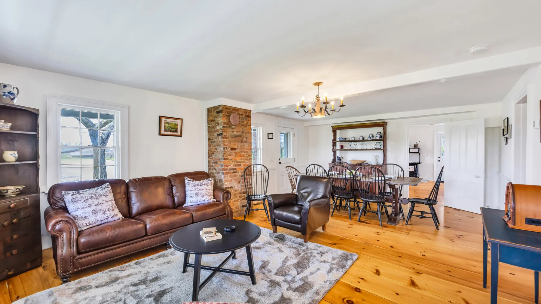 A living and dining area with leather seating, a table, and exposed brick.
