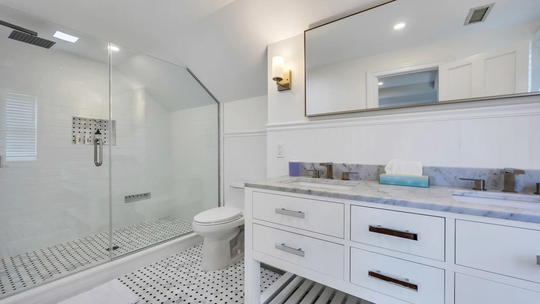 A bright bathroom with a glass shower and a white vanity.