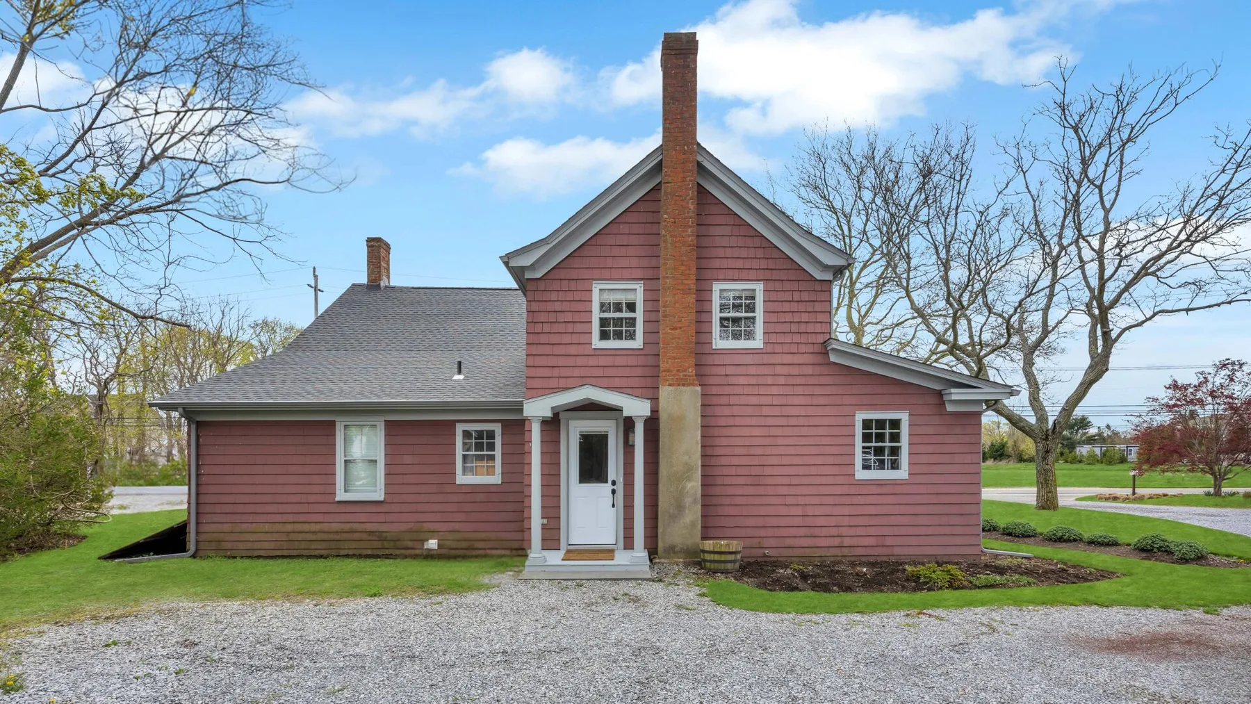 A pink house with a central chimney stands beside a gravel driveway.
