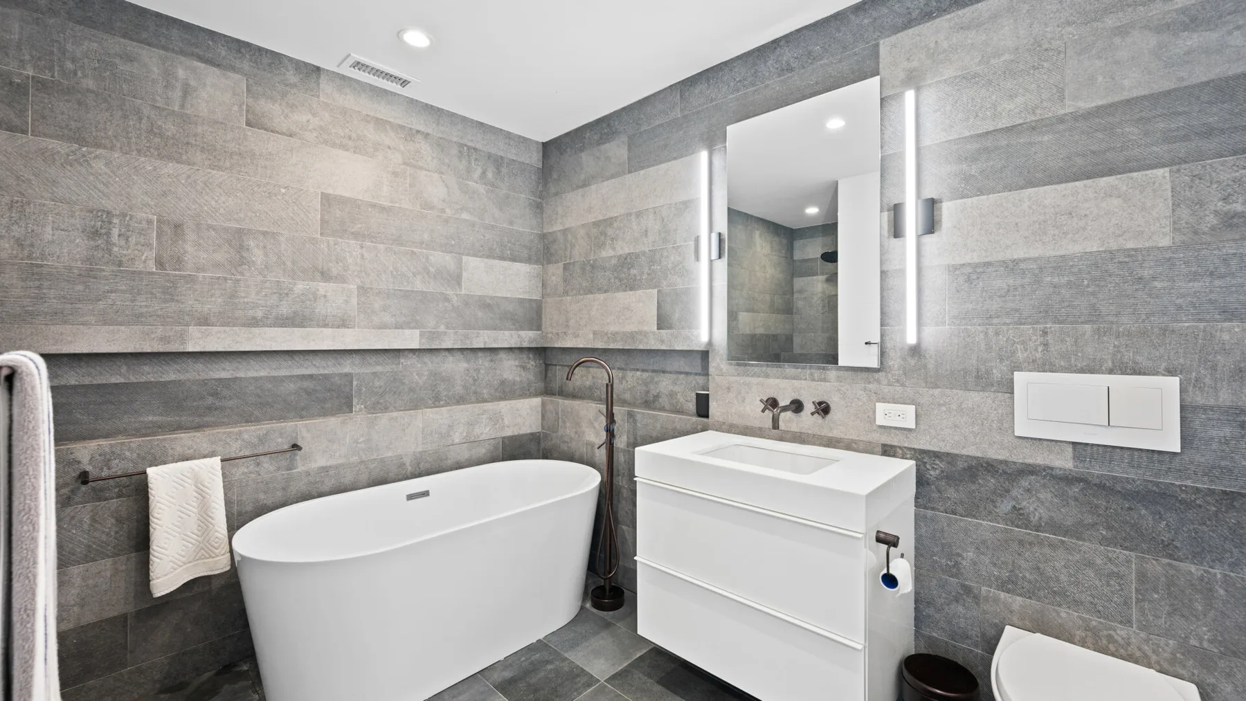A modern bathroom with a freestanding bathtub and a white vanity.