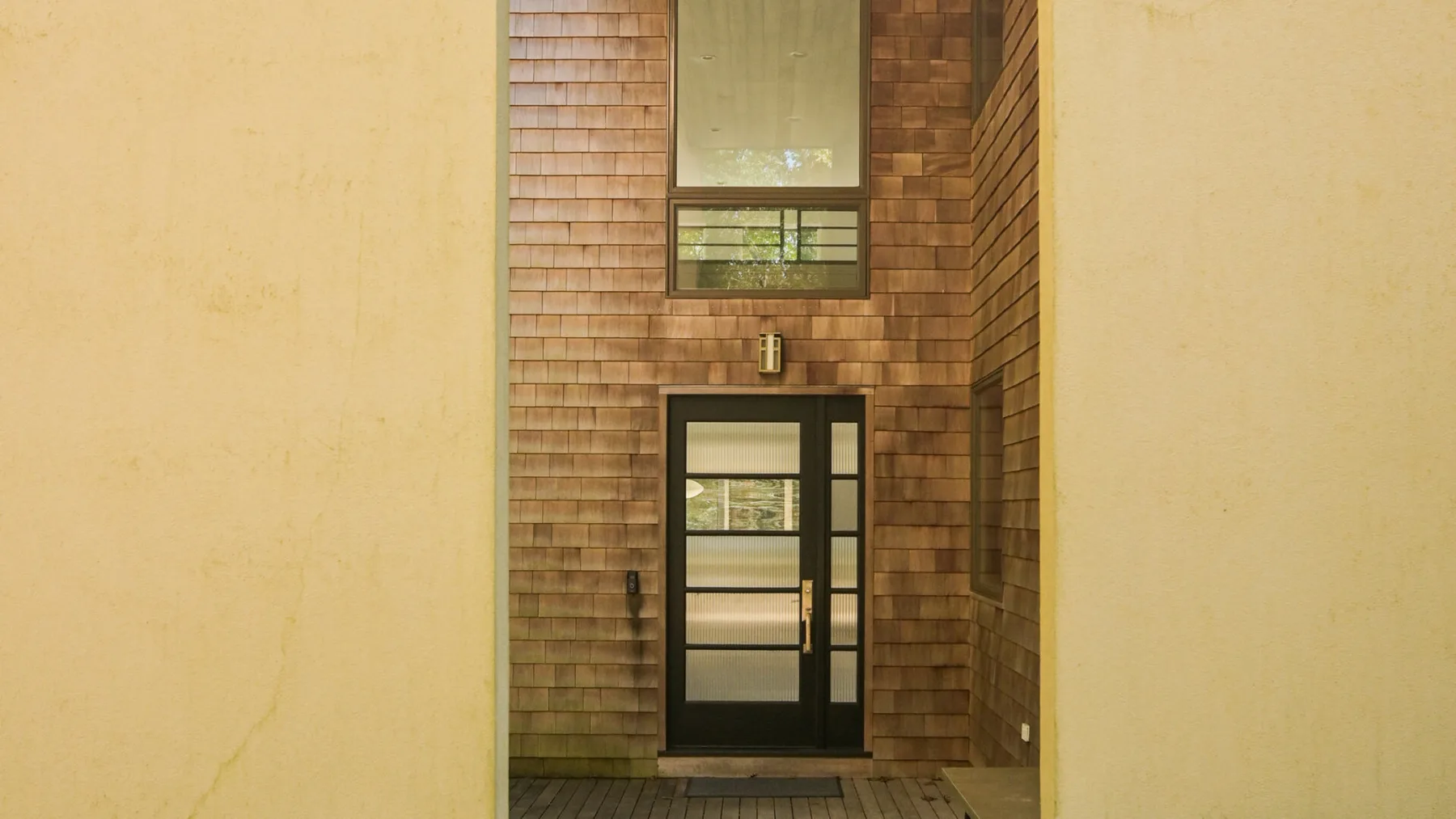 A narrow entryway with a dark door and a window above it.