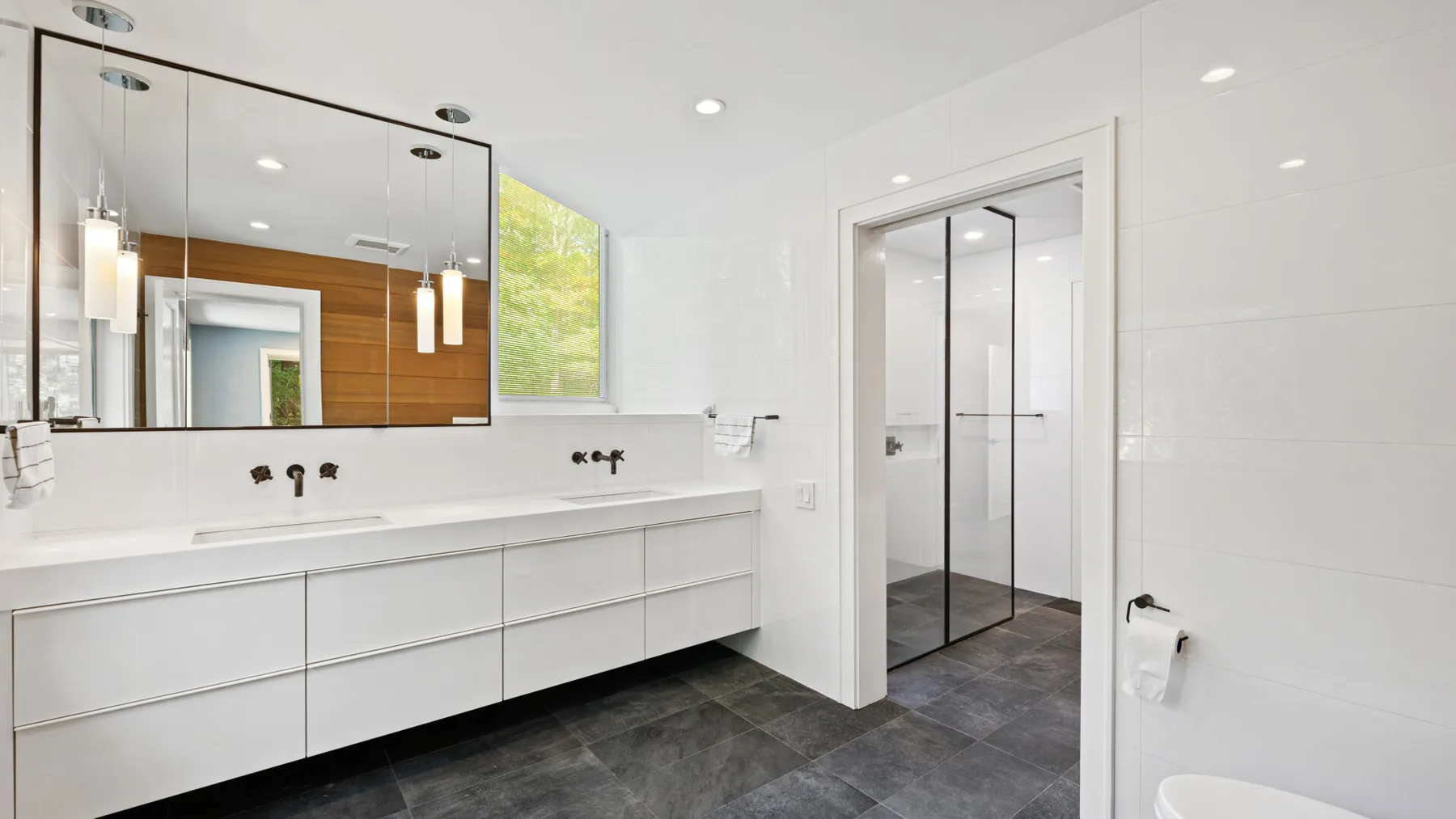 A bright bathroom with a long vanity and a glass shower.