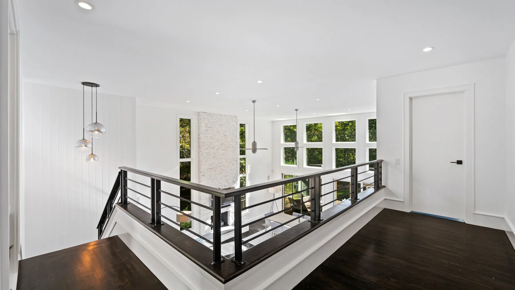 A bright interior landing overlooks a lower level through a dark railing.