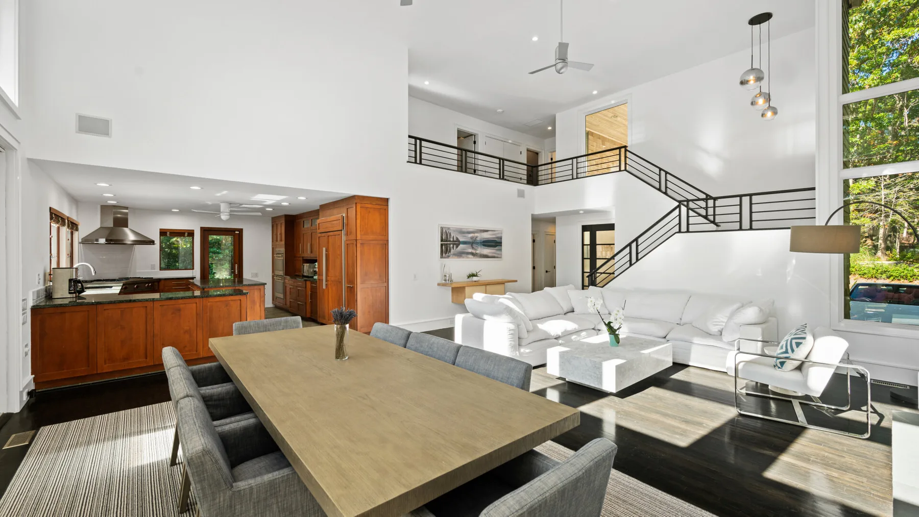 An open-plan dining and living area features a long table and white seating.