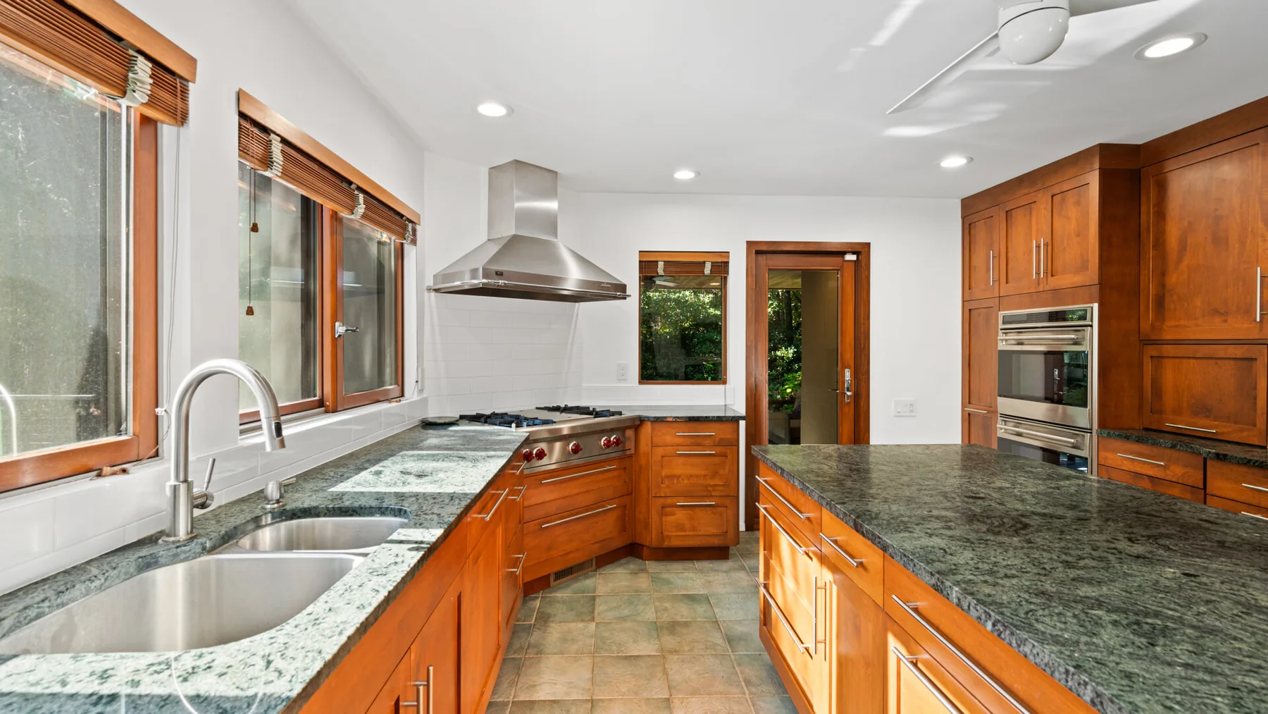 A kitchen with wood cabinets, stone countertops, and a central island.