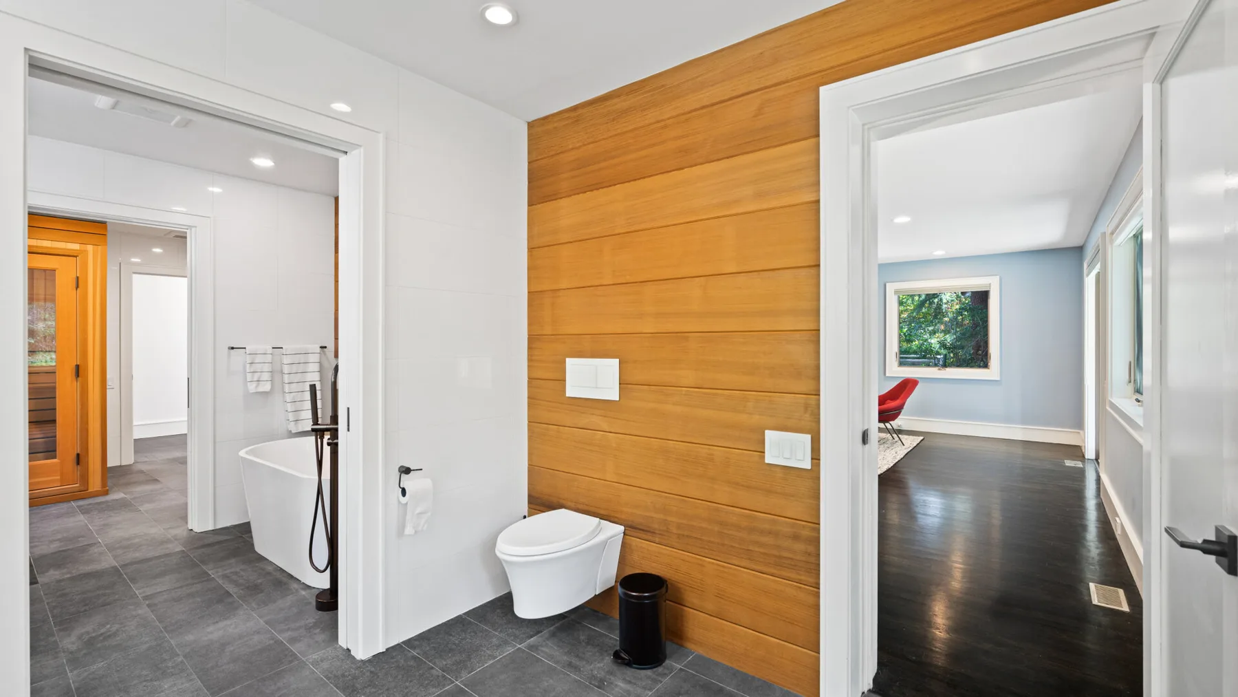 A bathroom with a toilet beside a wood-paneled wall.