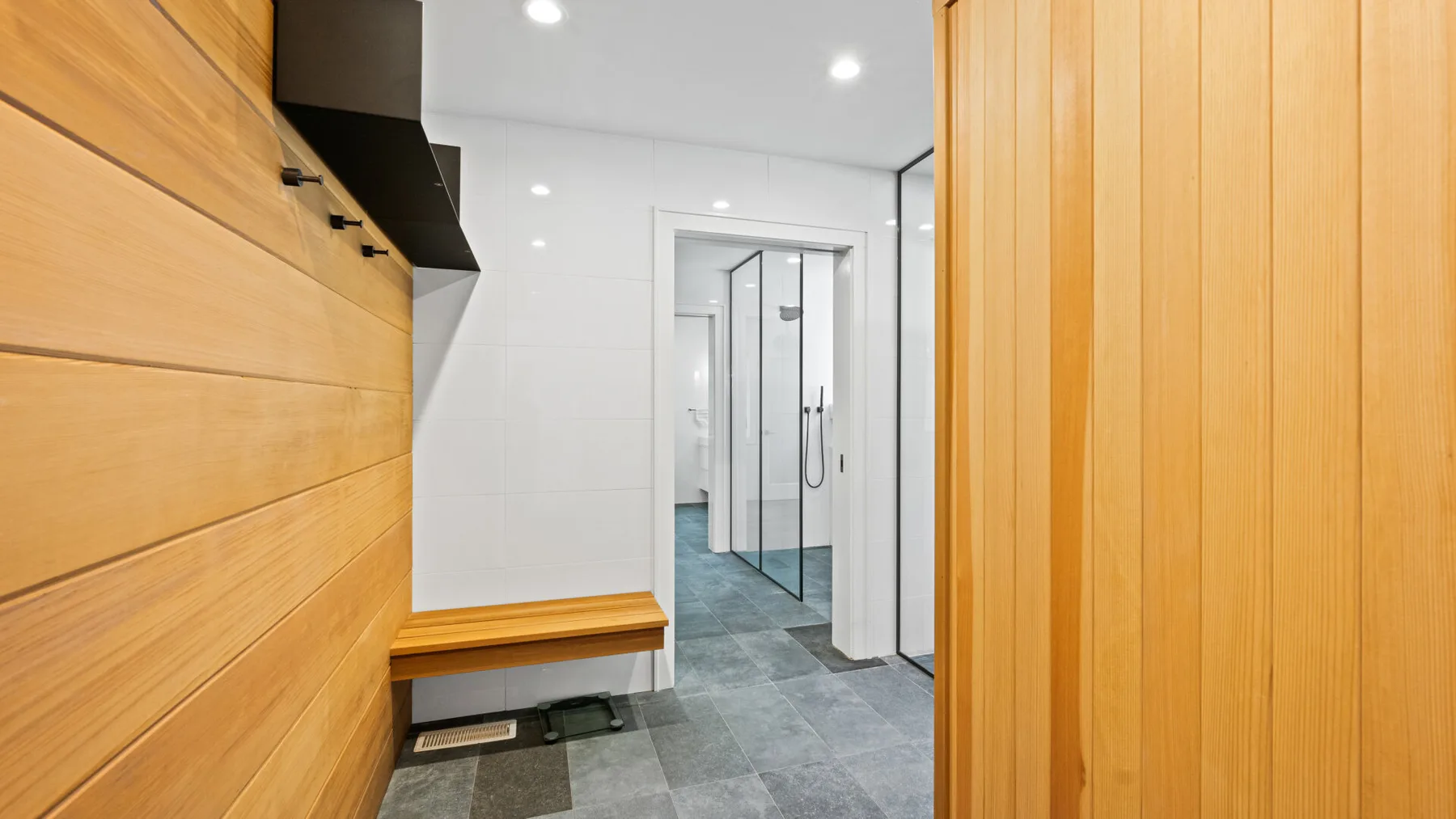 A bright changing room opens onto a shower area, with wood-paneled walls and gray tile.