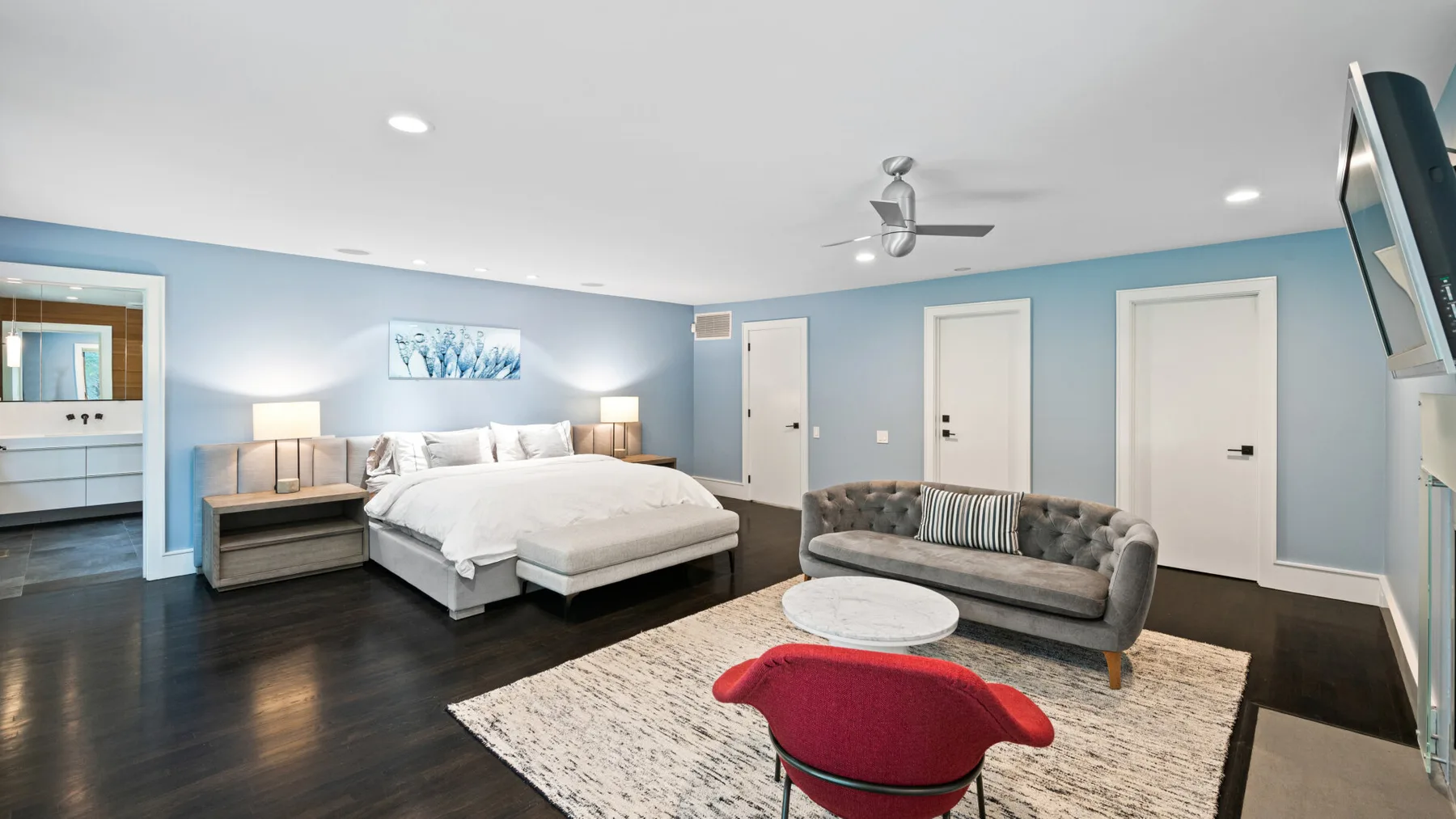 A bedroom with a large bed and a seating area on a rug.